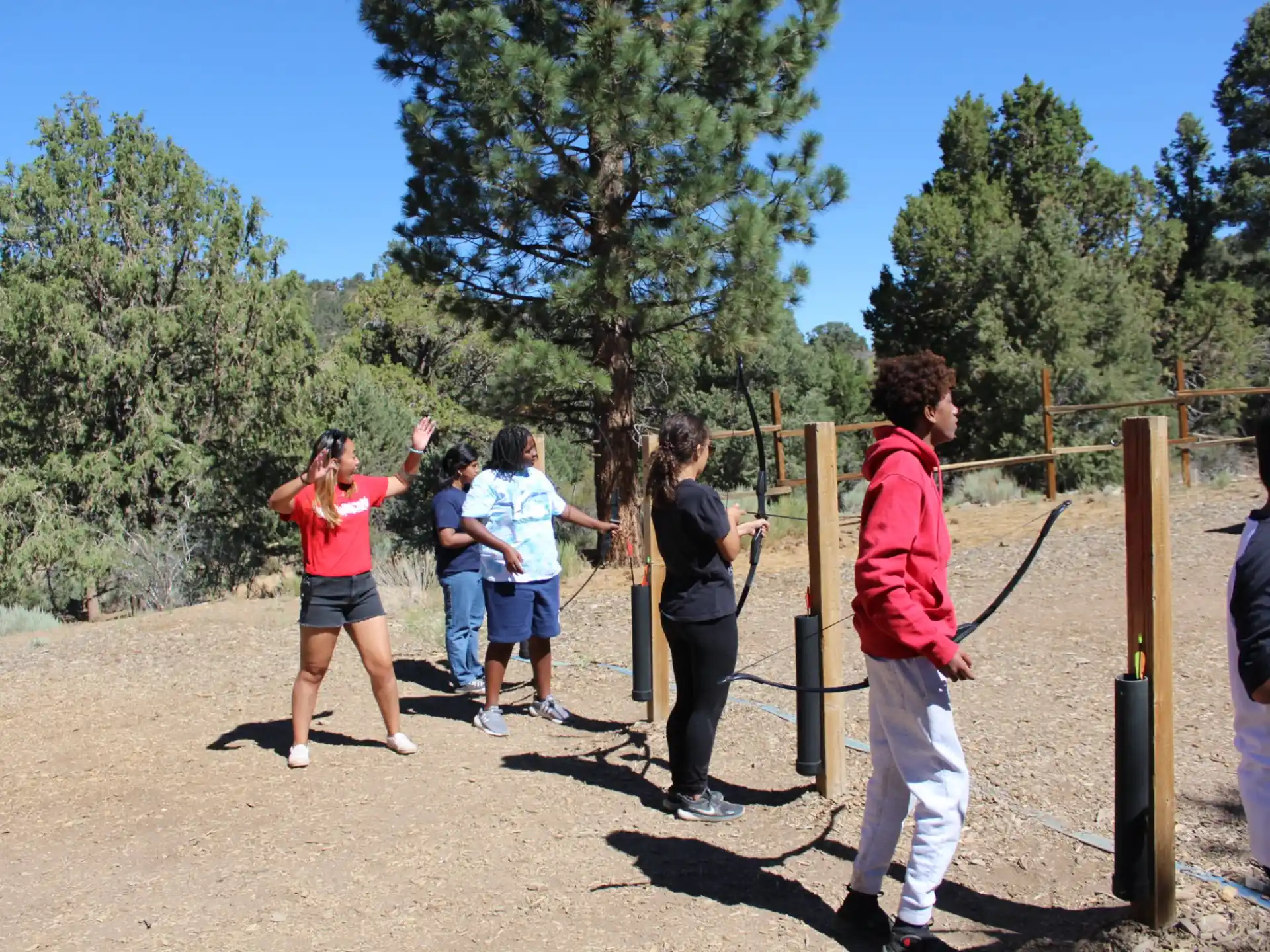 a group of people standing on a dirt path with trees and grass