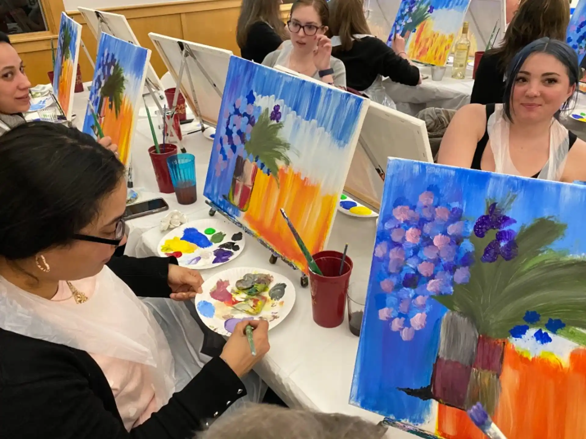 a group of people sitting at a table painting