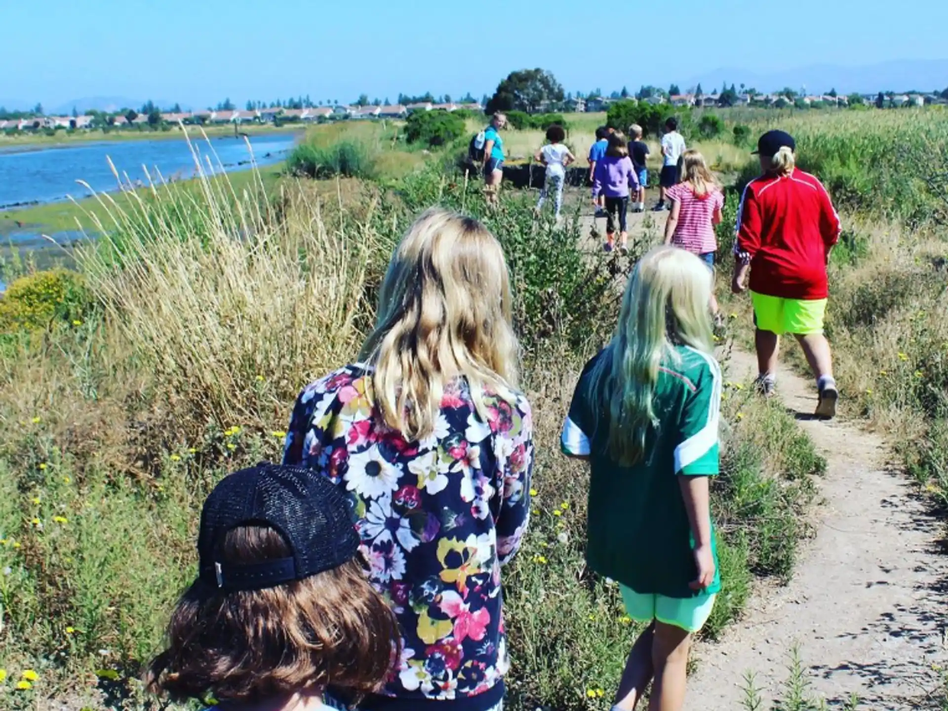 a group of people walking on a path near a body of water