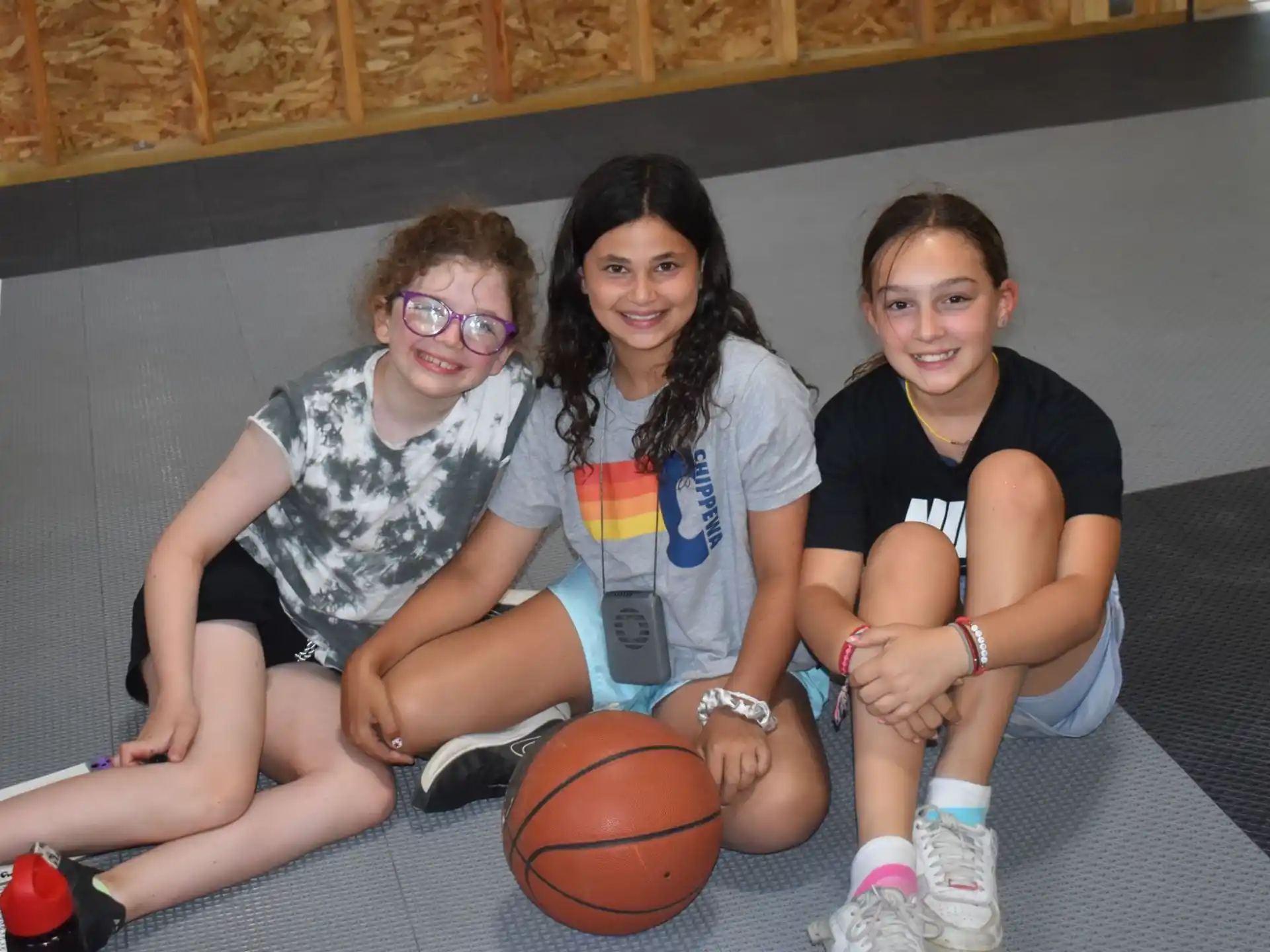 a group of women sitting on a bench with a basketball