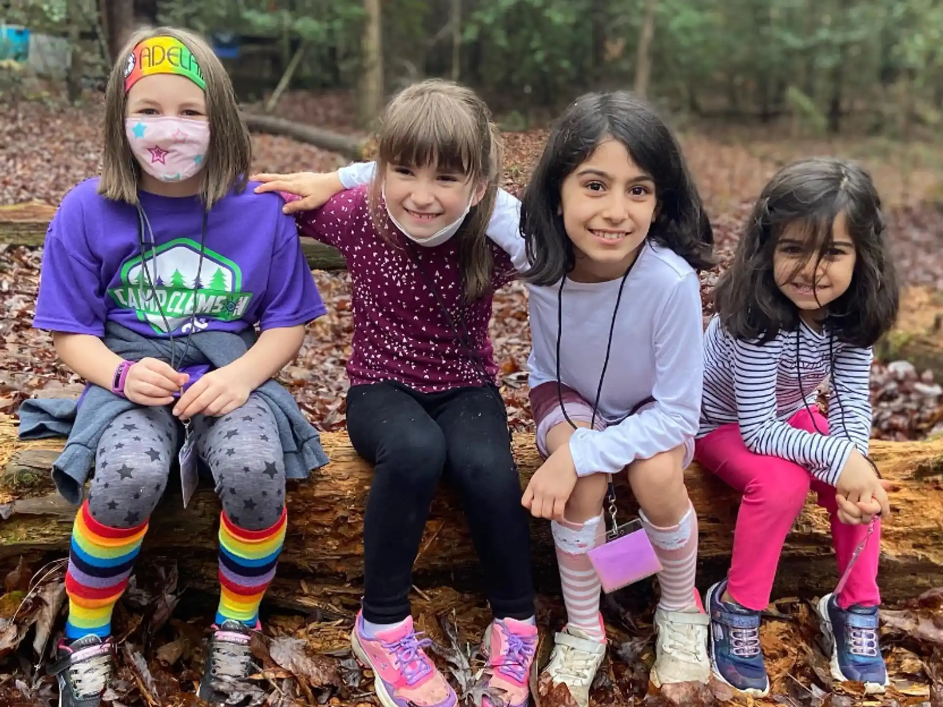 a group of girls sitting on a log posing for the camera
