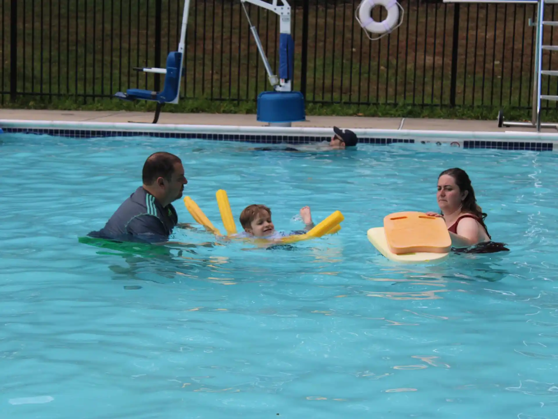a man and woman in a pool with a child in a yellow inner tube