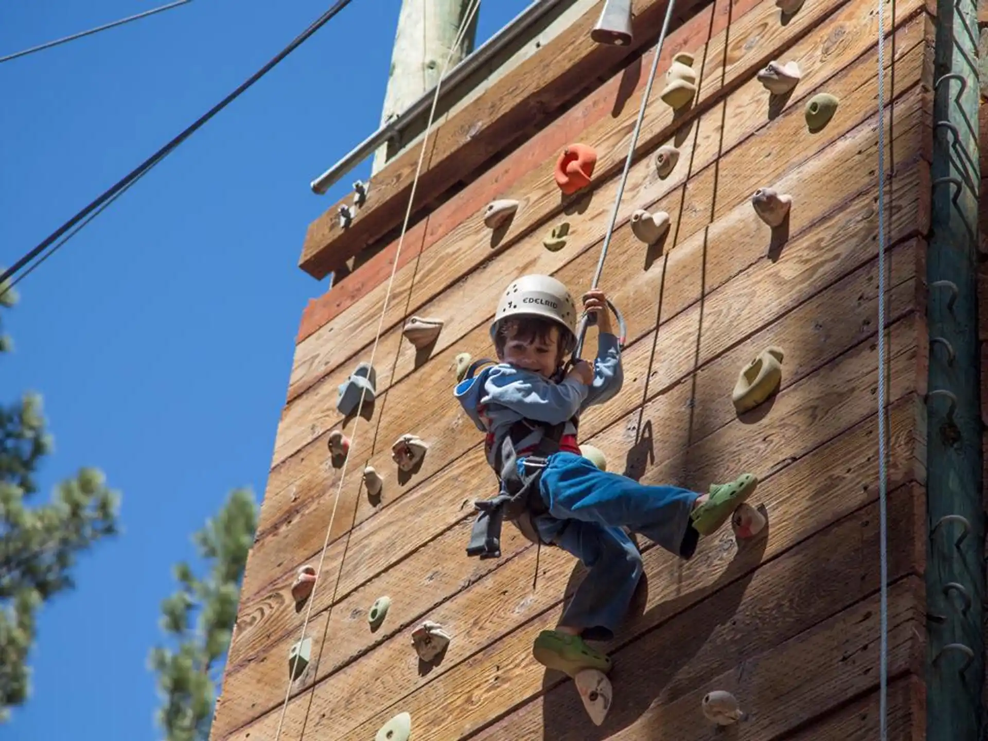 a young boy climbing a wooden wall