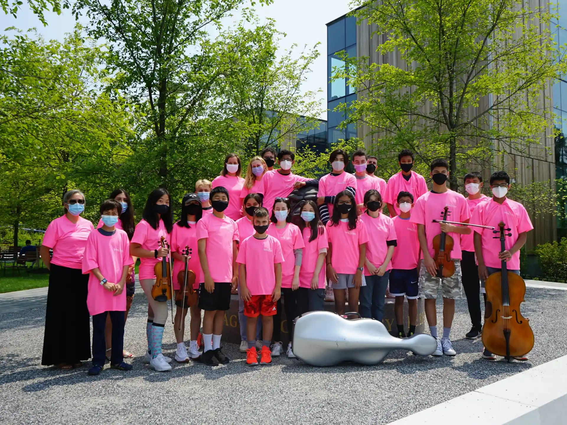 a group of people wearing pink shirts and holding instruments