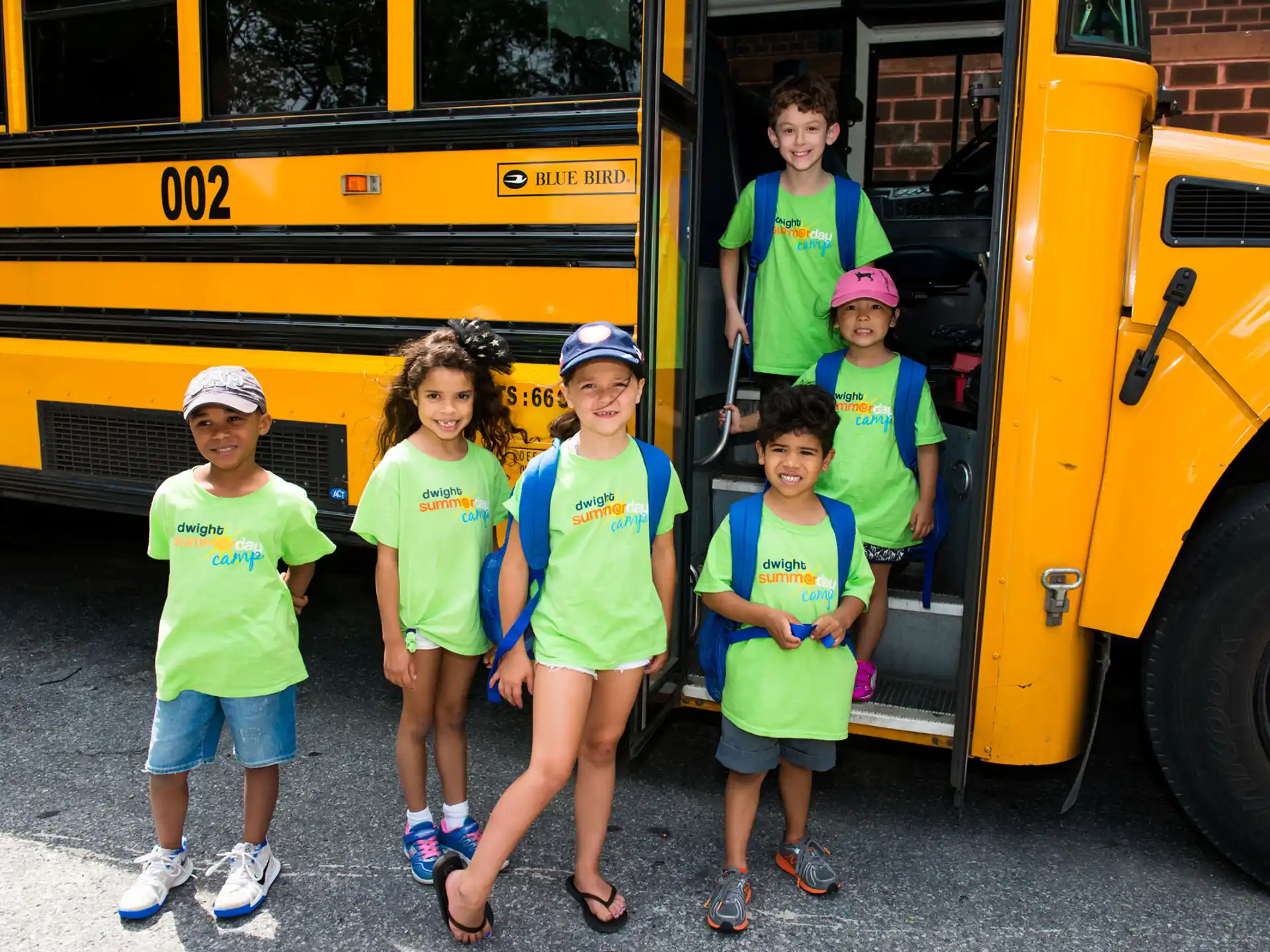 a group of children standing in front of a school bus