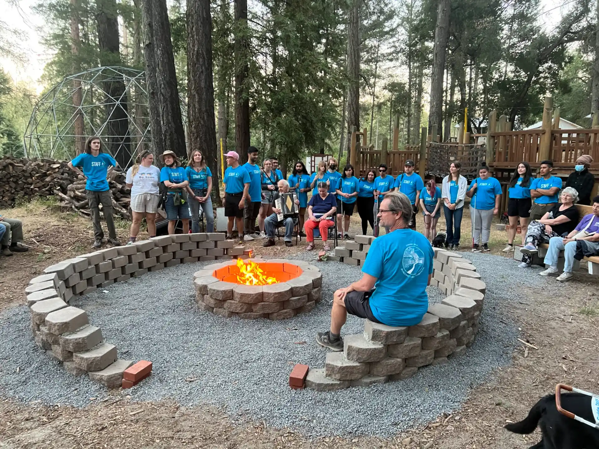 a group of people standing around a person sitting on a bench