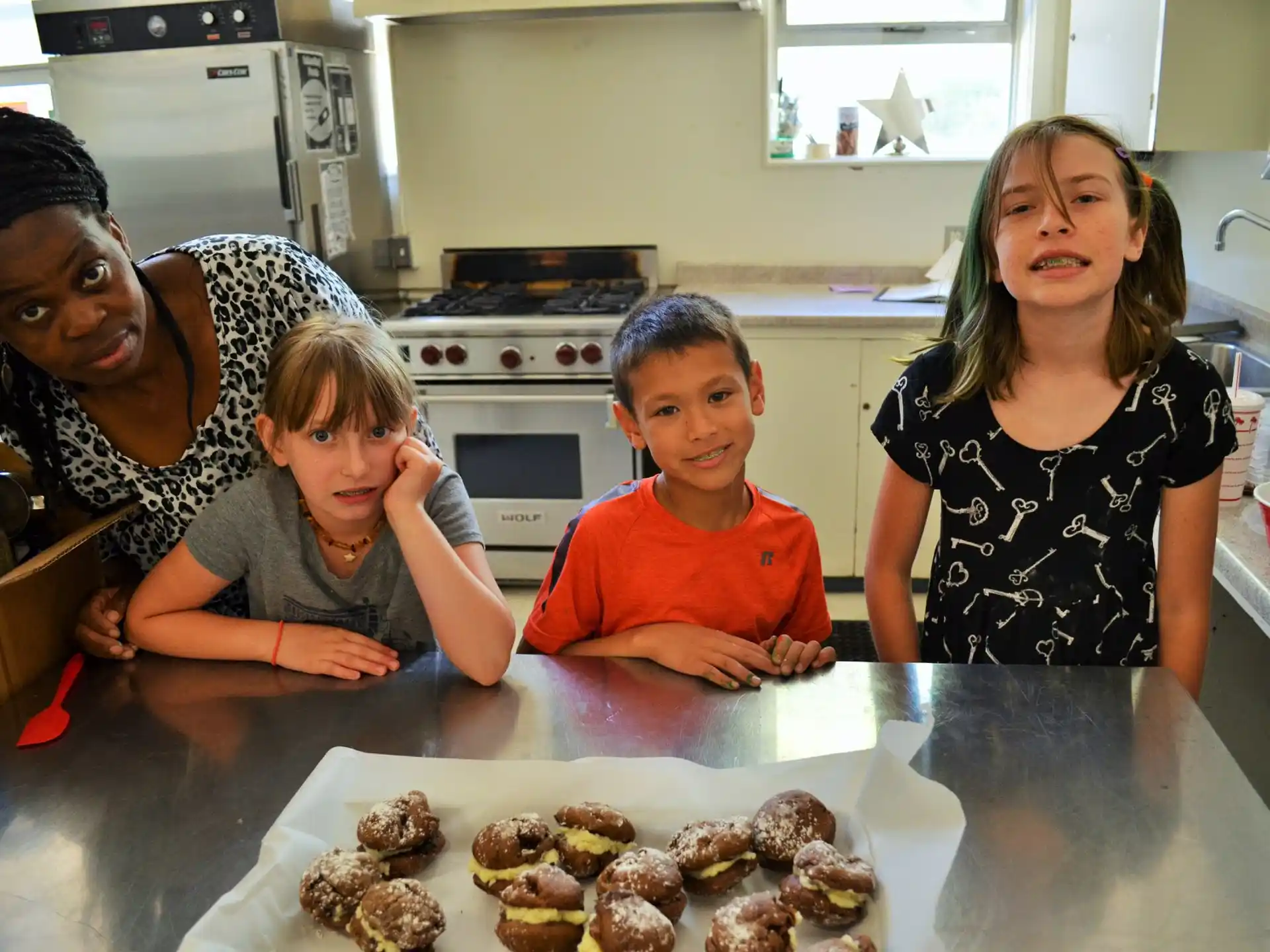 a woman and two children with a tray of donuts