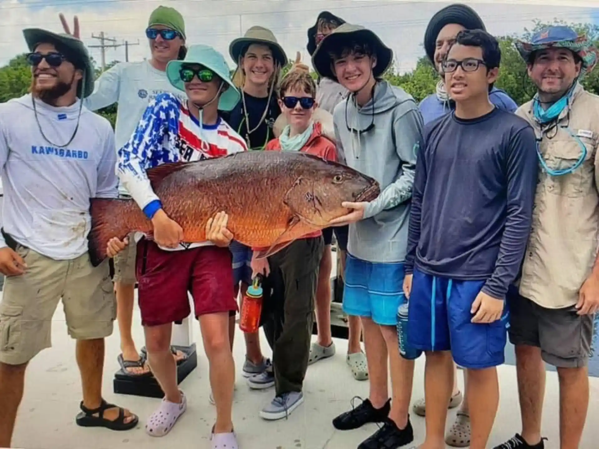 a group of people holding a large fish
