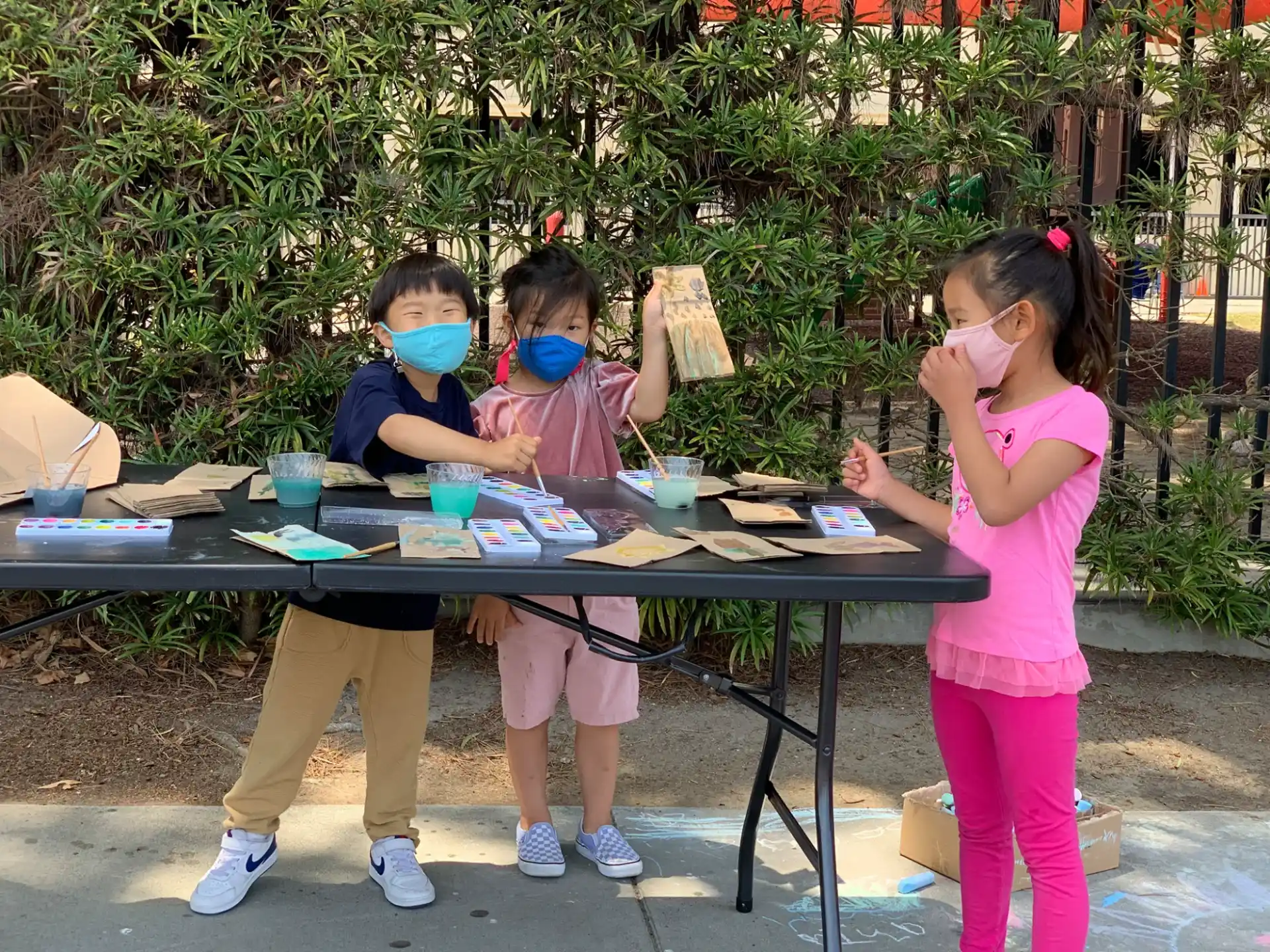 a group of children sitting at a table outside