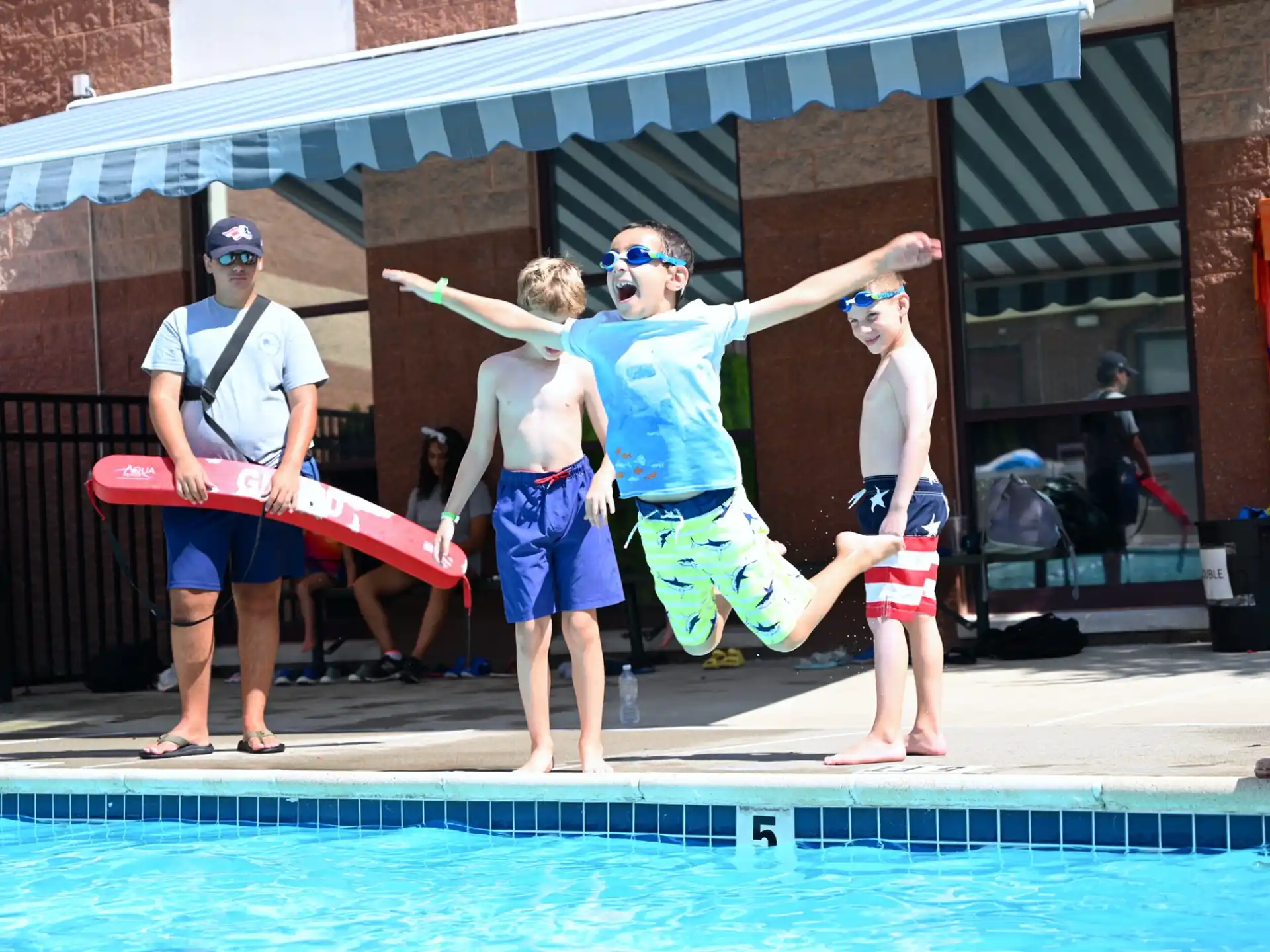 a group of people standing around a pool with a person holding a surfboard