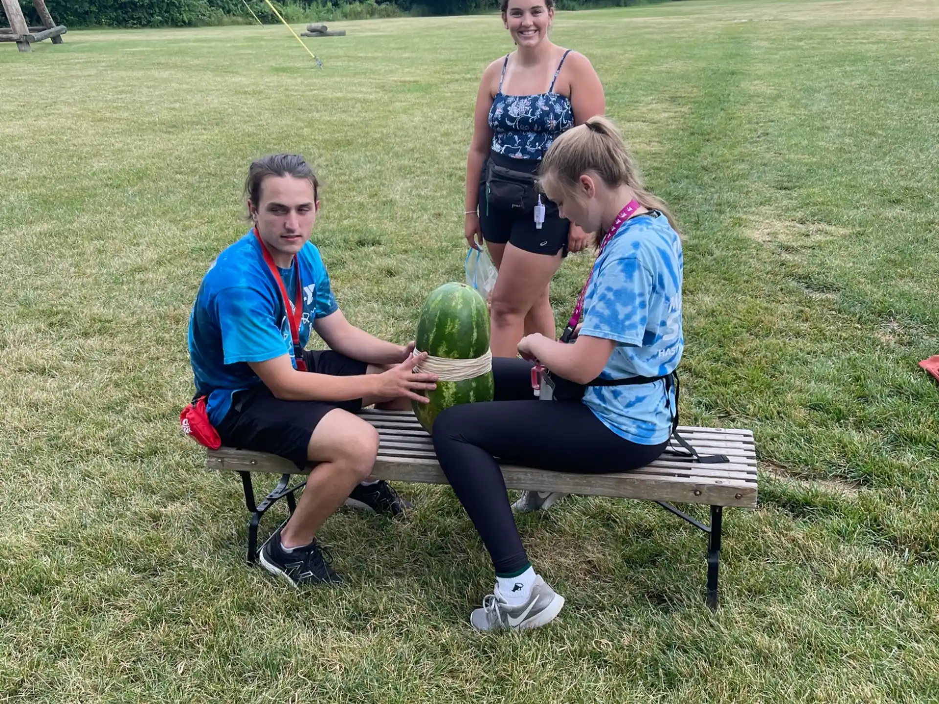 a group of people sitting on a bench holding a large green vegetable
