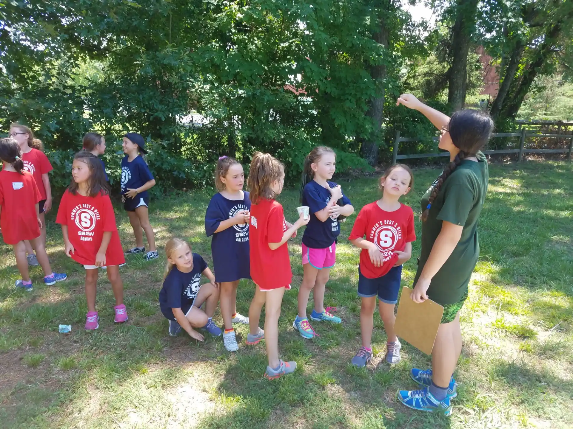 a group of children standing in a grassy area