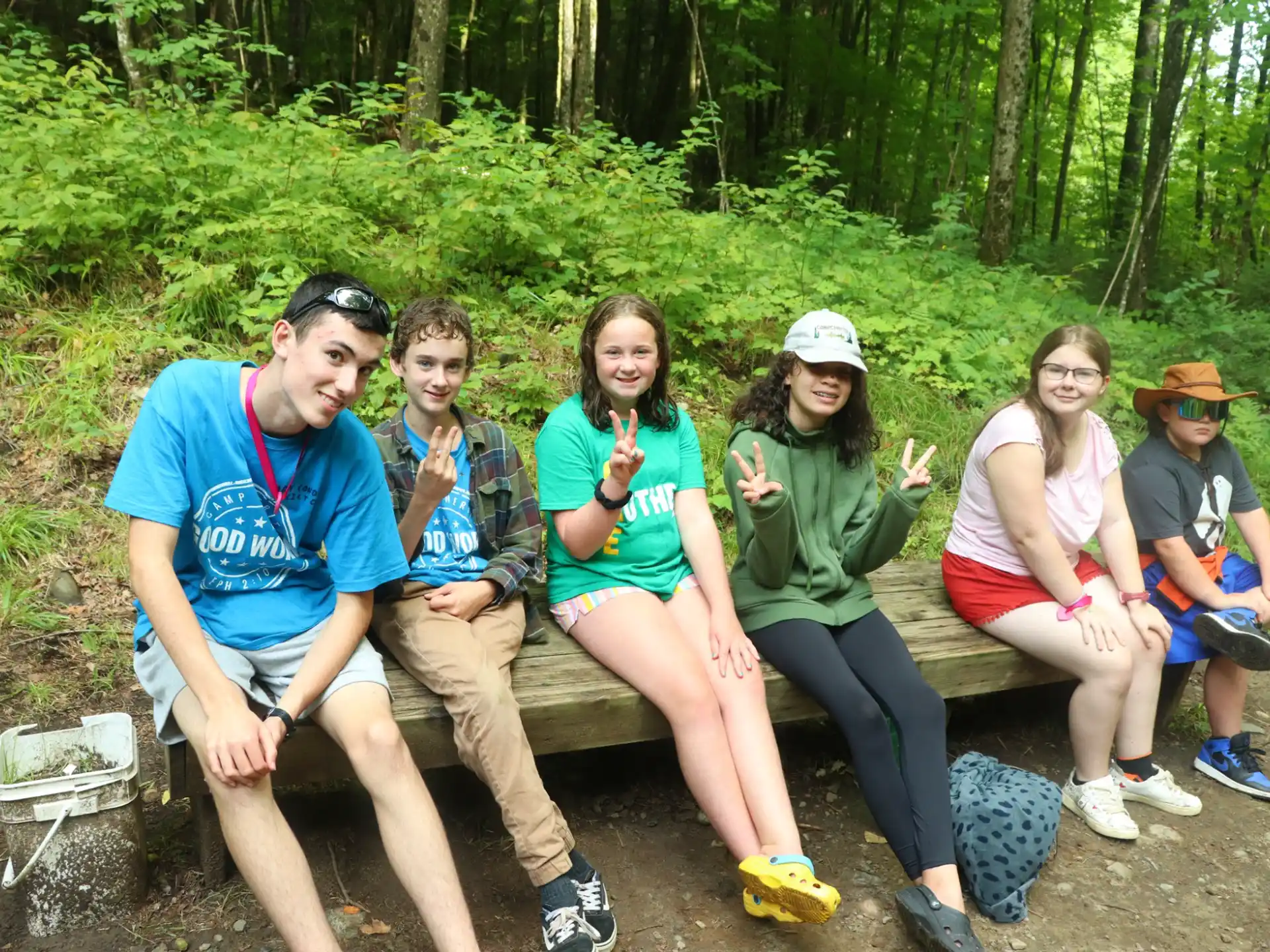 a group of people sitting on a bench in the woods