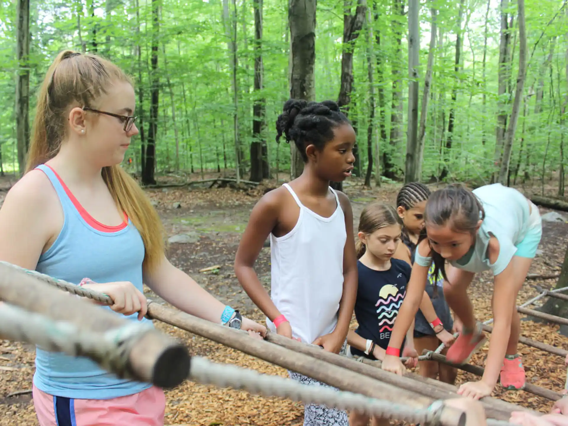 a group of people playing with a rope in the woods