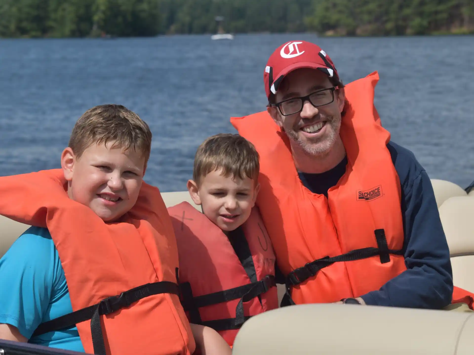a man and two boys in life jackets on a boat