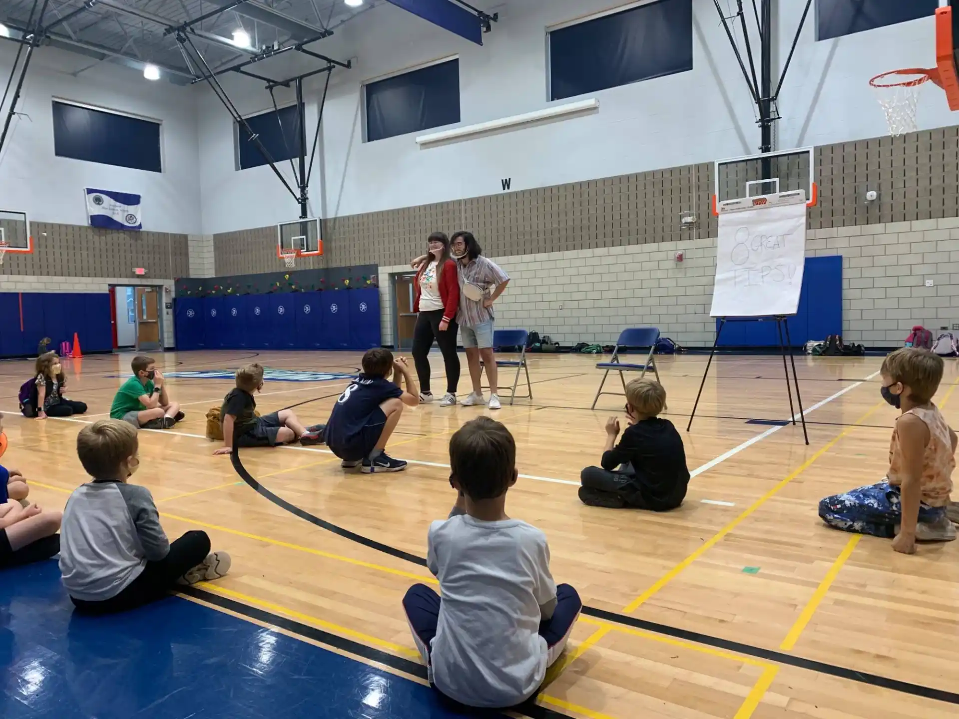 a group of people sitting on the floor in a gym