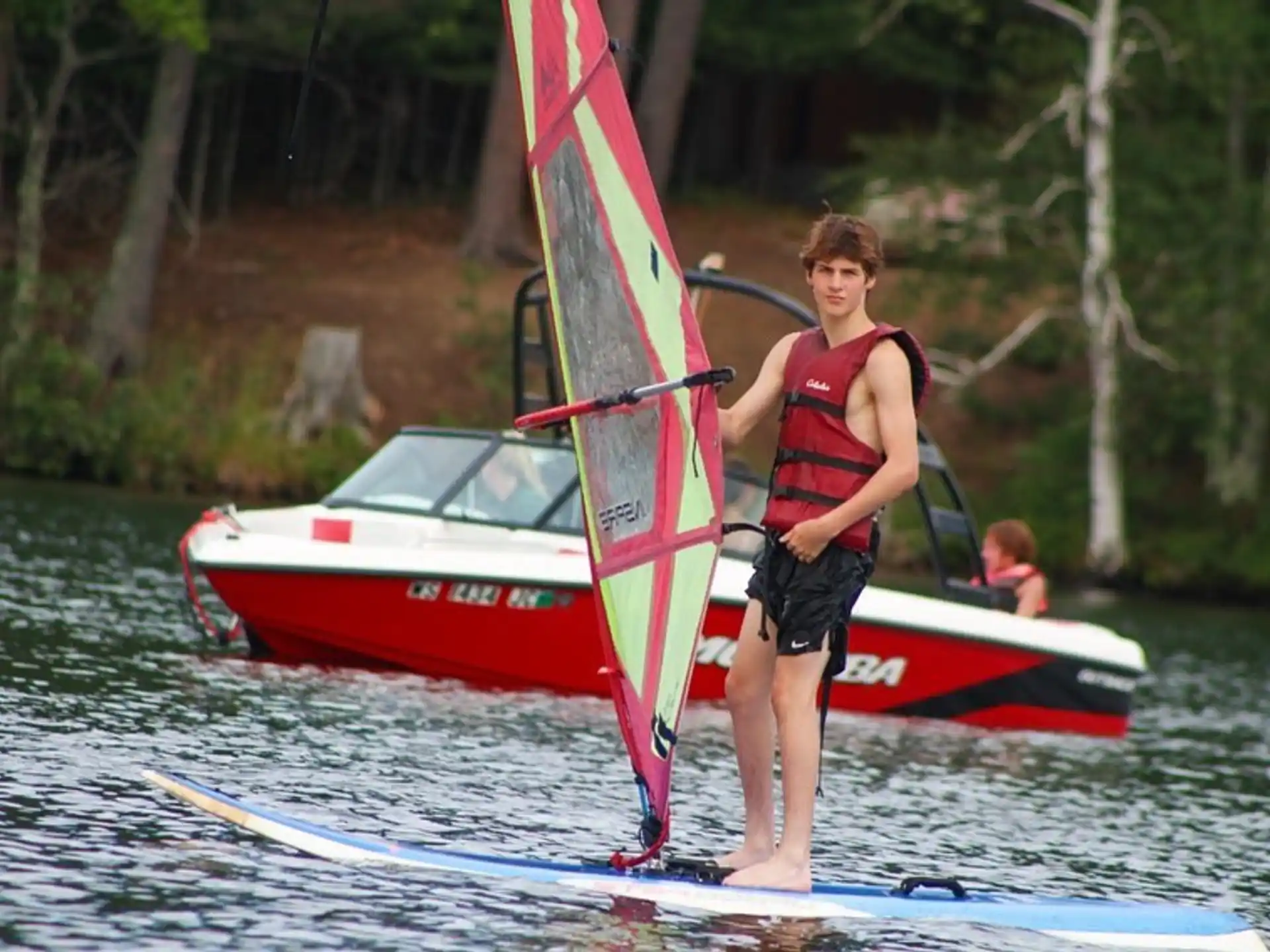a boy on a surfboard holding a sail