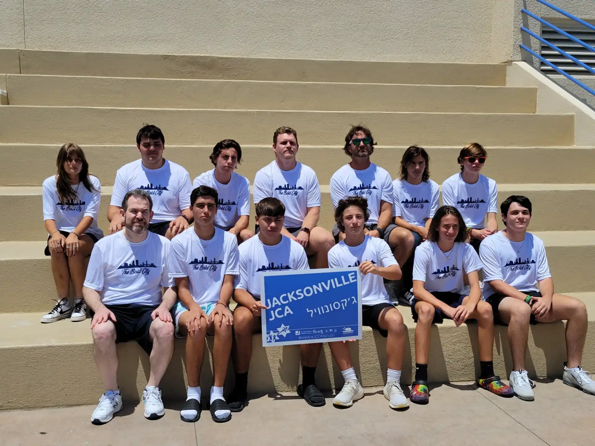a group of people sitting on stairs holding a sign