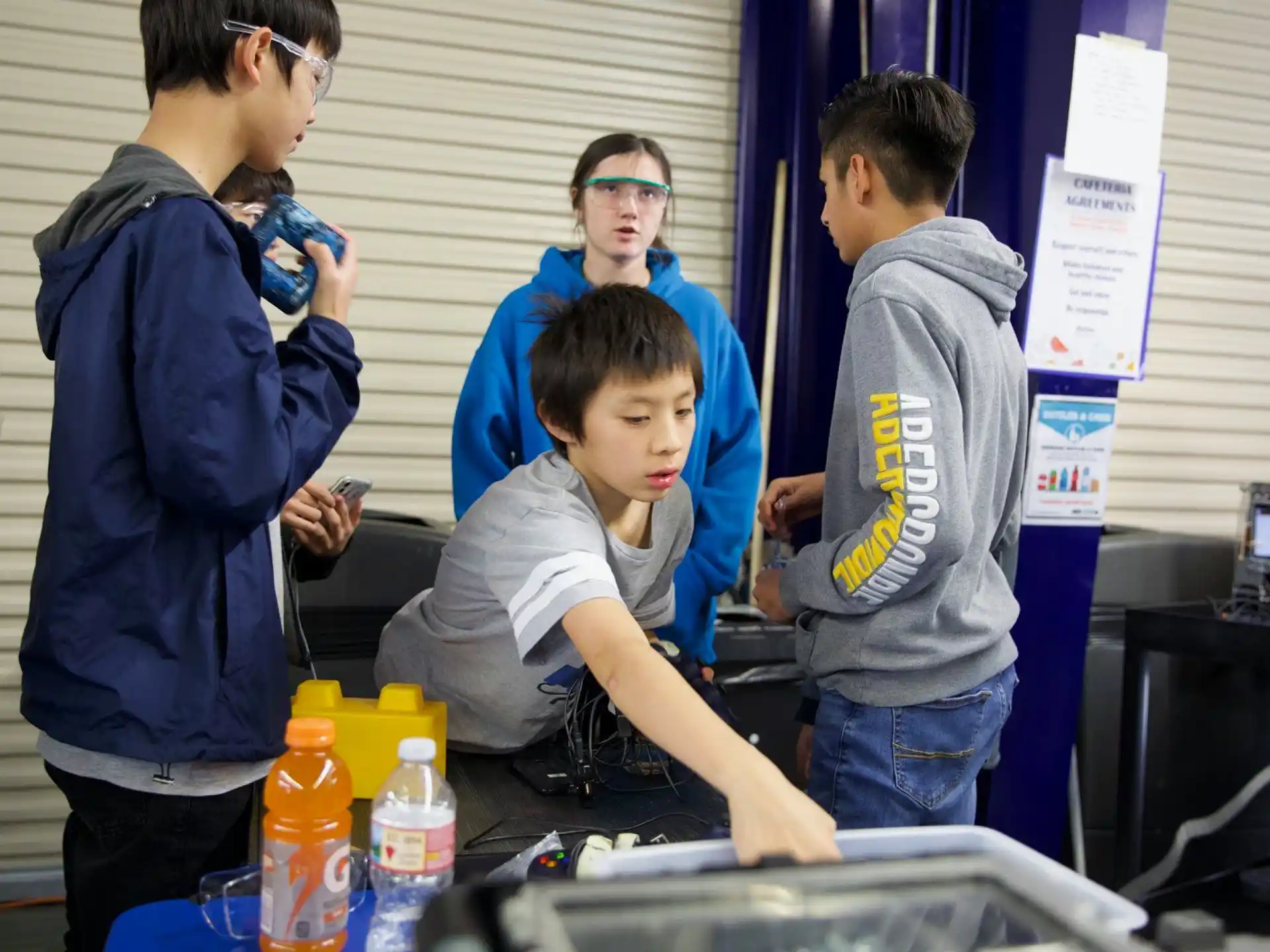 a group of people standing around a table with a person sitting at it