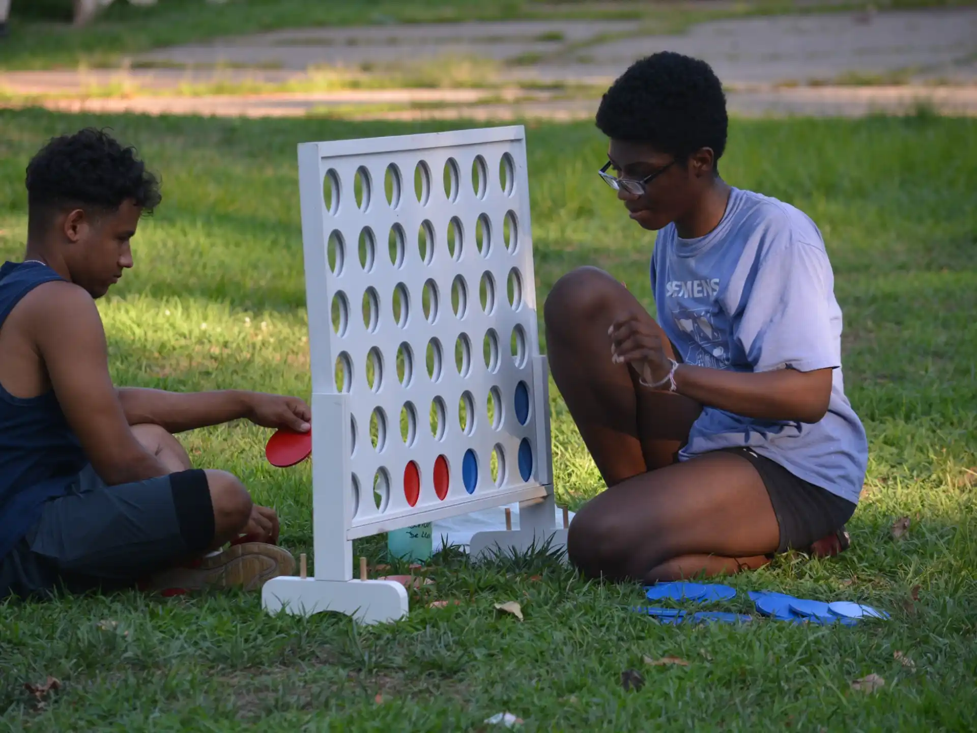 a couple of men sitting on the grass next to a sign