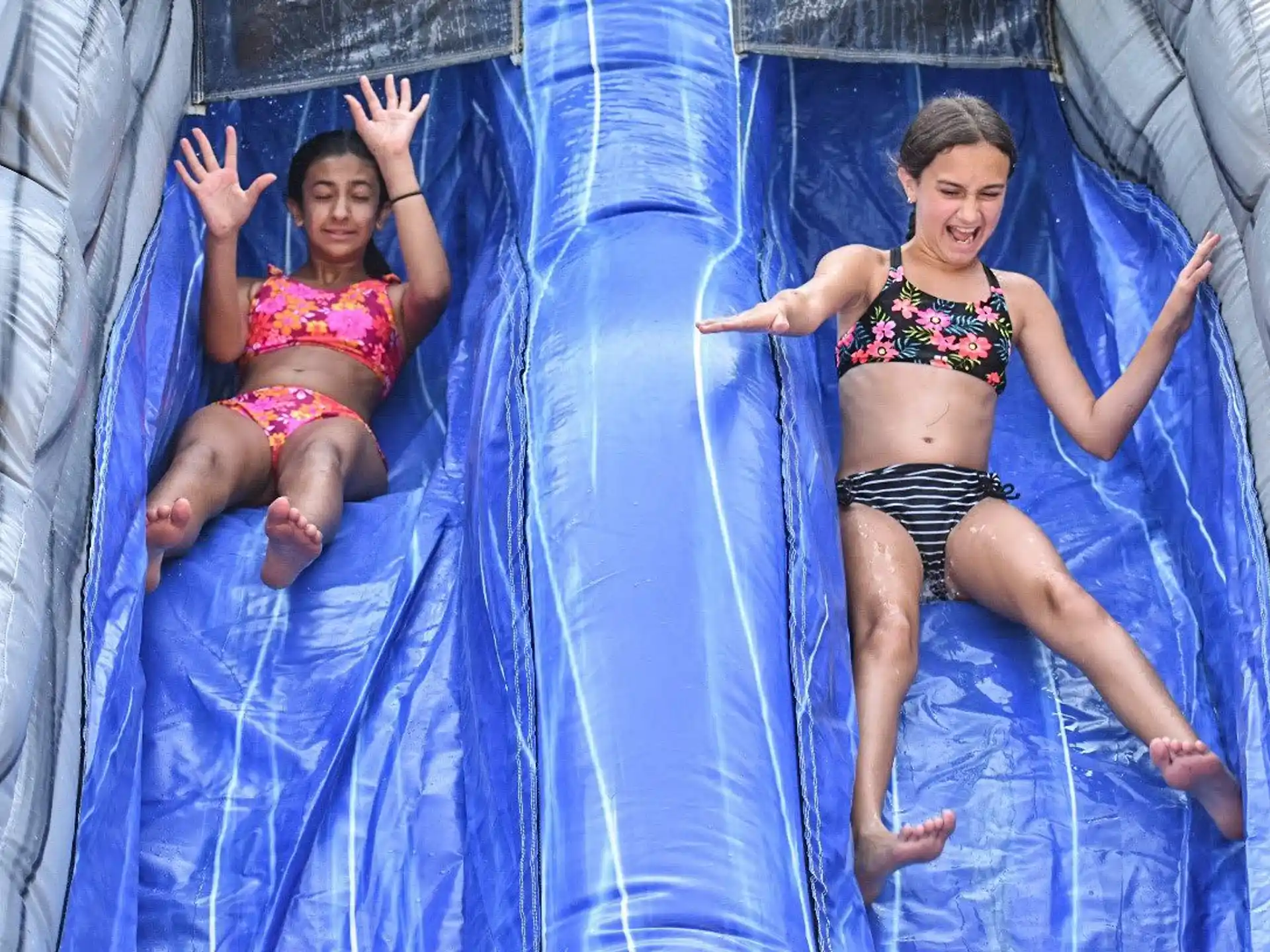 a couple of women in swimsuits lying on a blue and white blanket