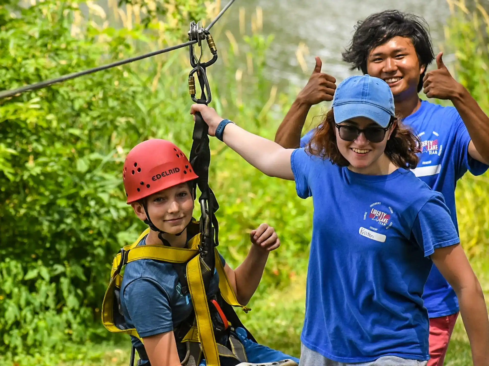 a person and a boy with a harness and a helmet on a zip line