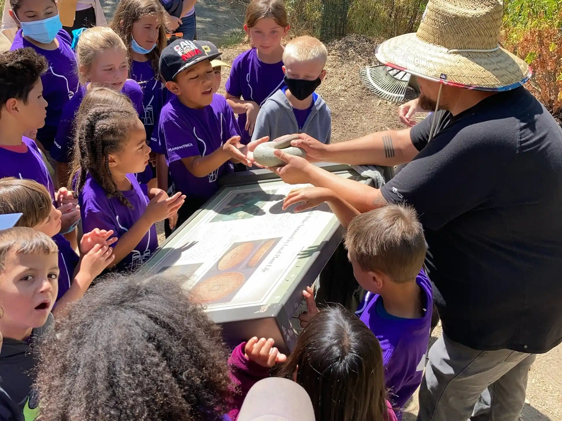 a person showing a group of children something on a table