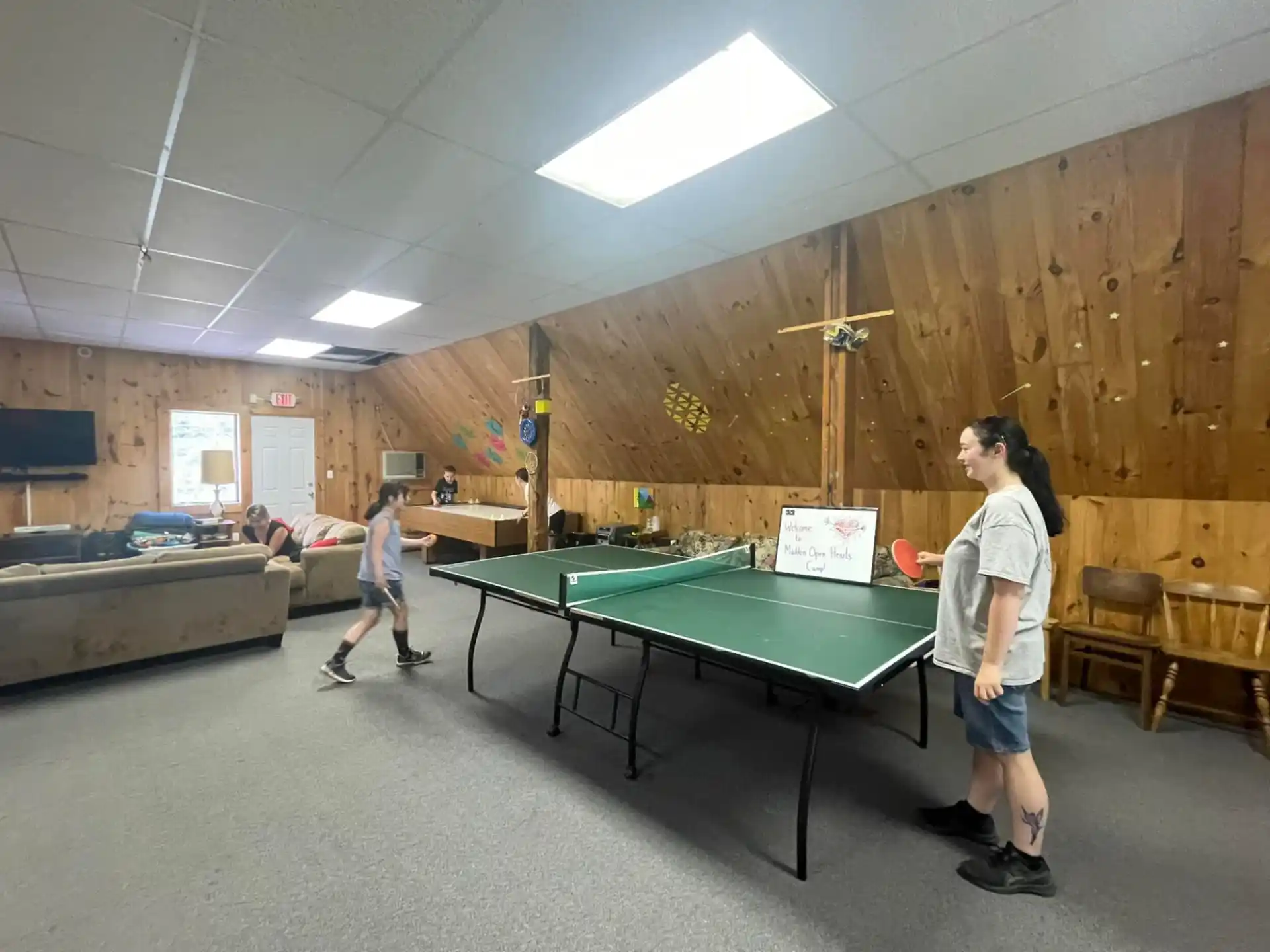 a man and a boy playing ping pong in a room with a wood wall and a wood