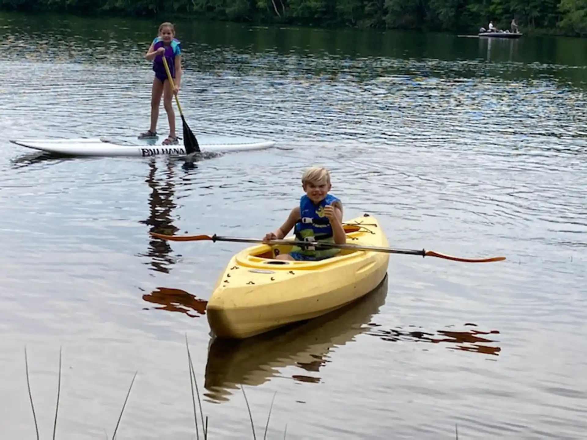 a couple of kids paddle on a canoe