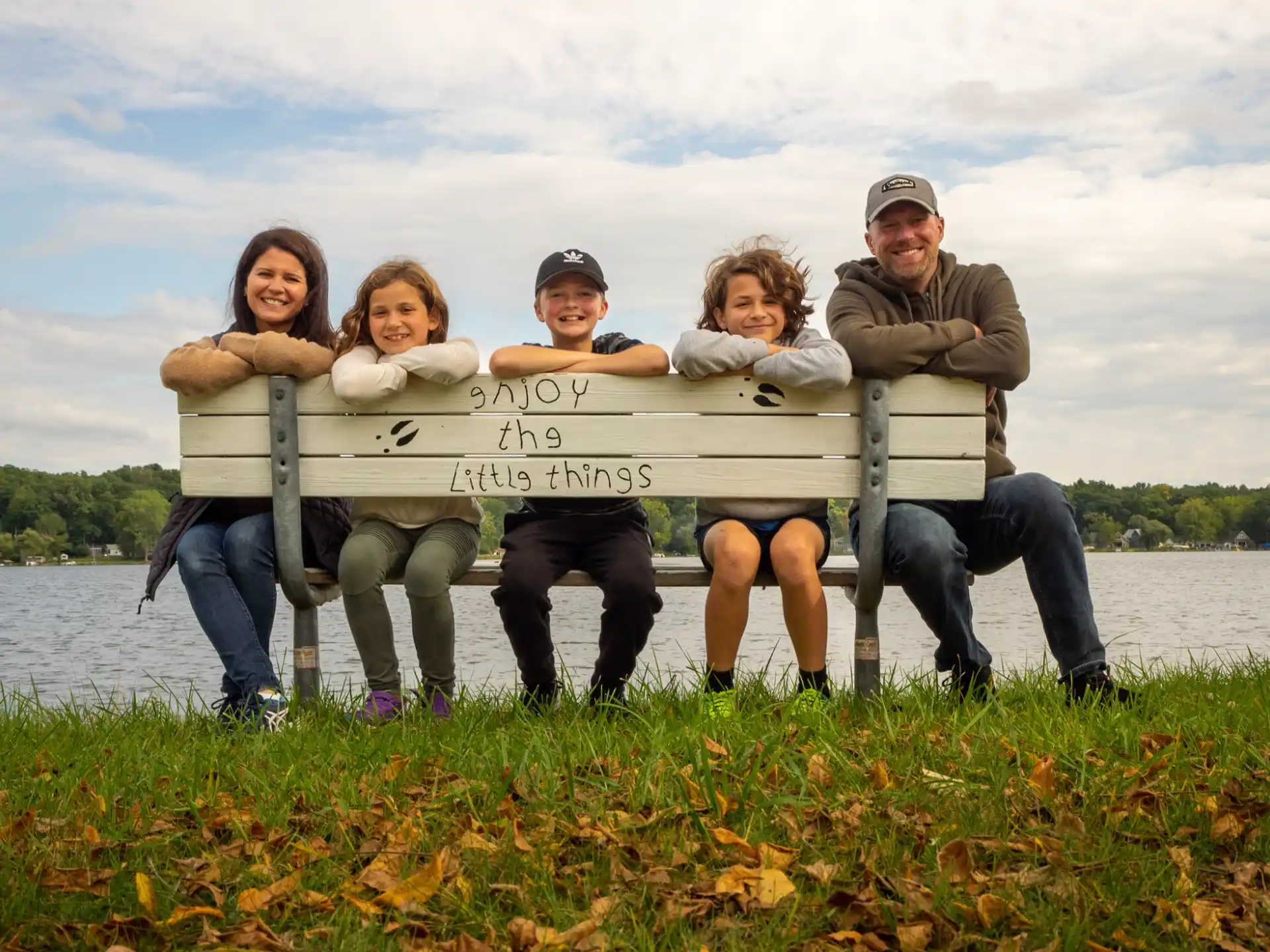 a group of people sitting on a bench by a lake