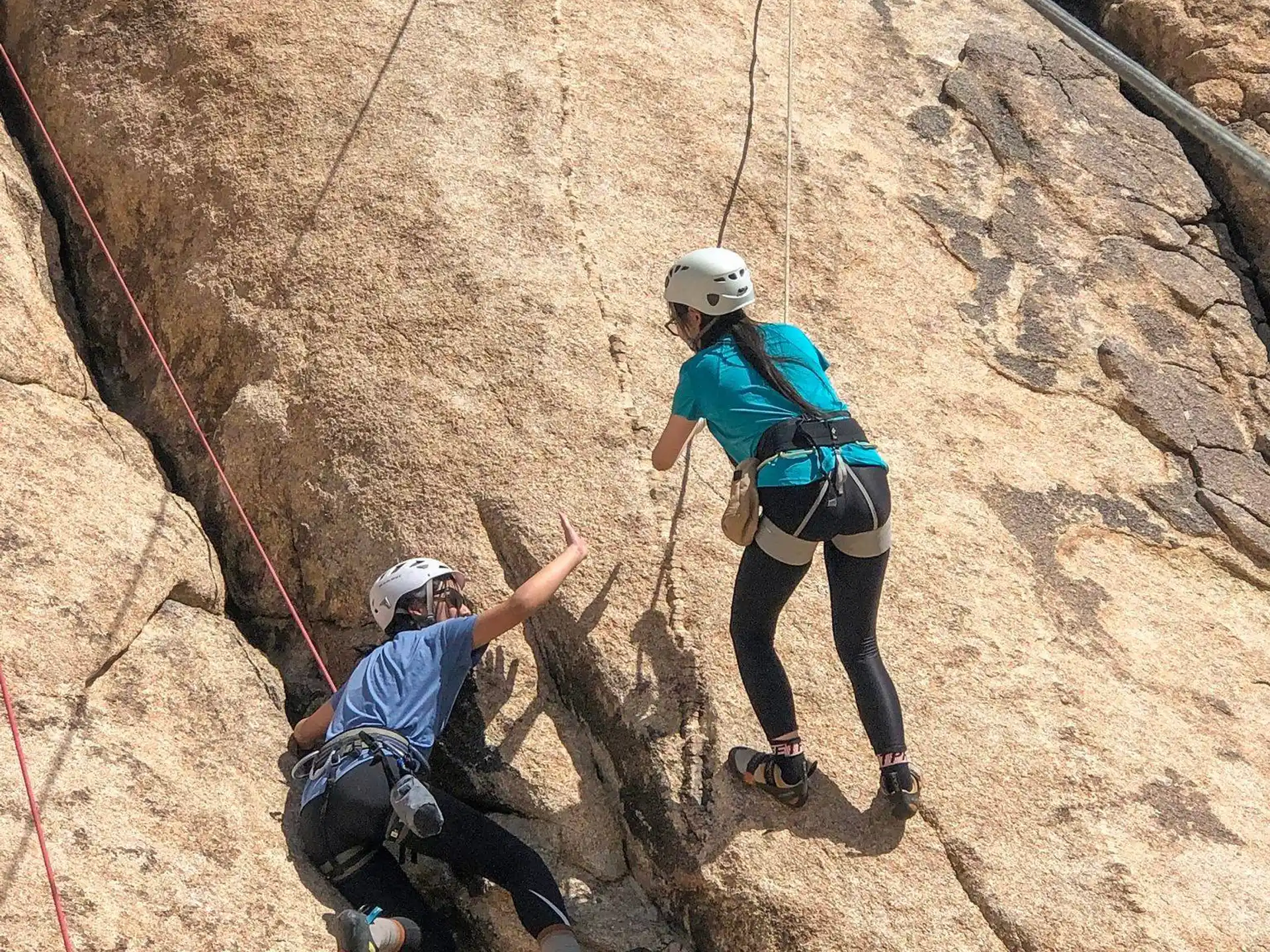 a couple of people climbing a rock wall