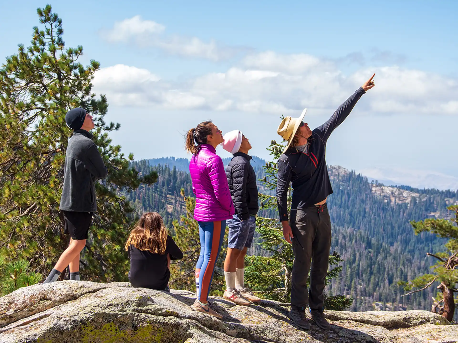 a group of people standing on a rock overlooking a valley