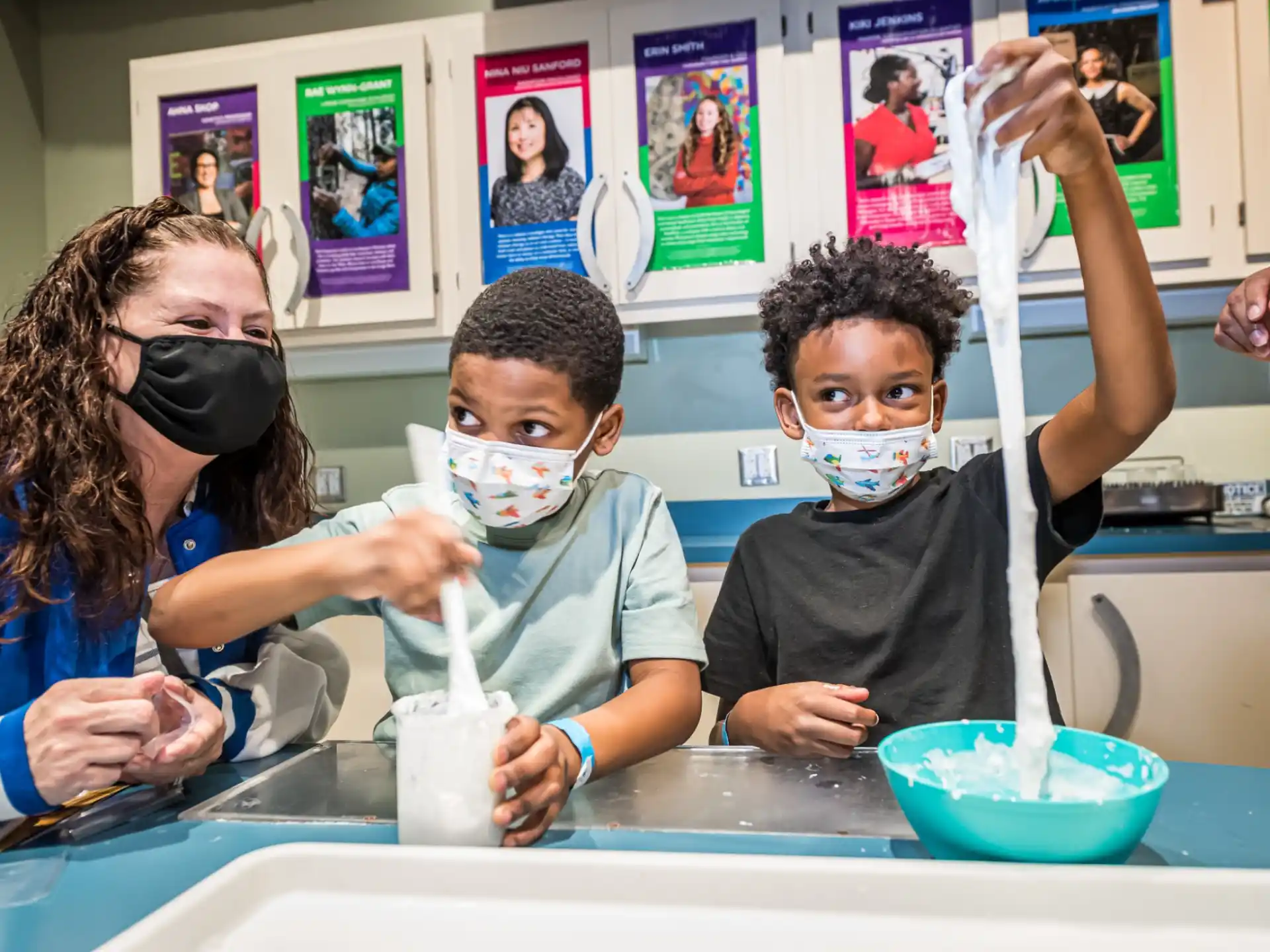 a group of kids wearing masks and drinking from a bowl
