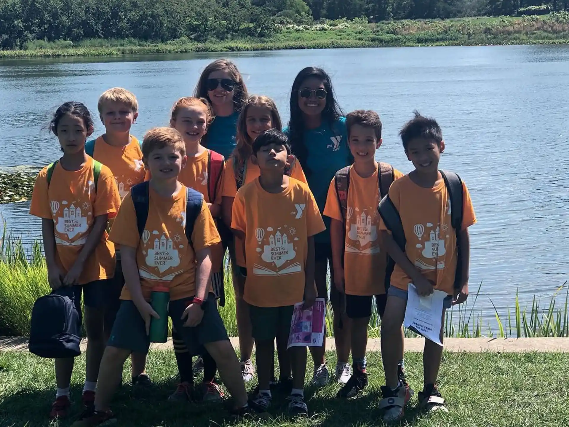 a group of people posing for a photo in front of a lake