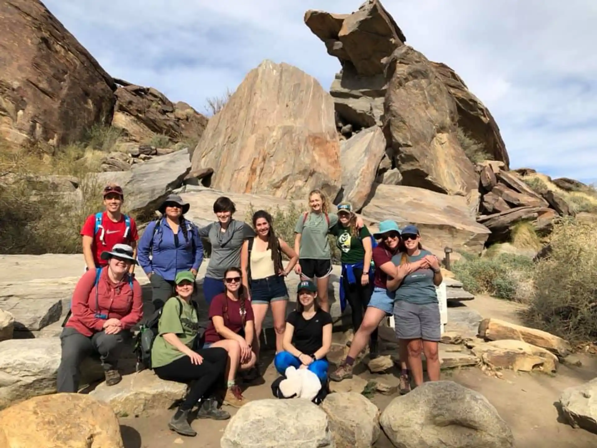 a group of people posing for a photo in front of a rocky mountain