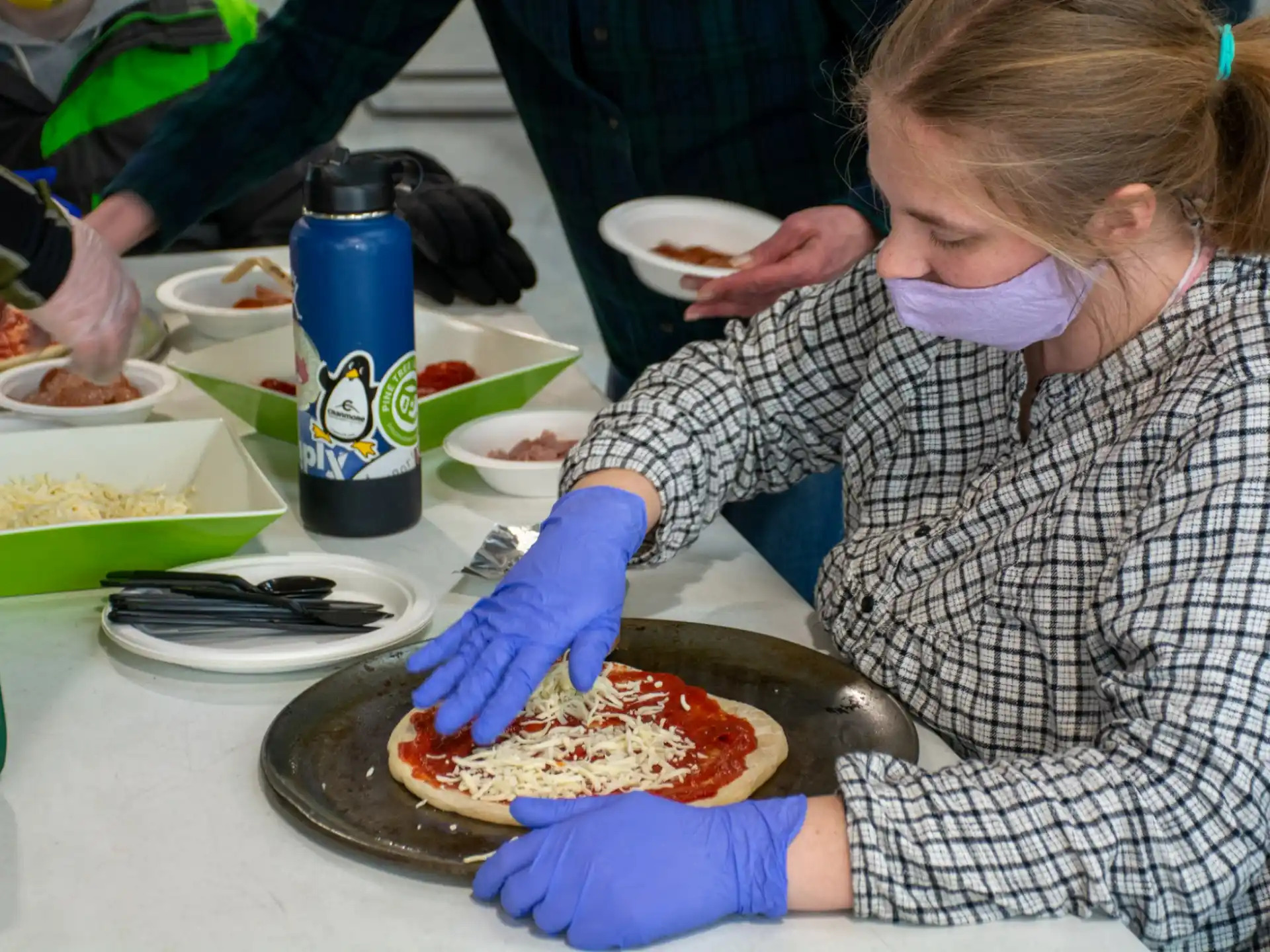a person in a surgical scrubs preparing a pizza