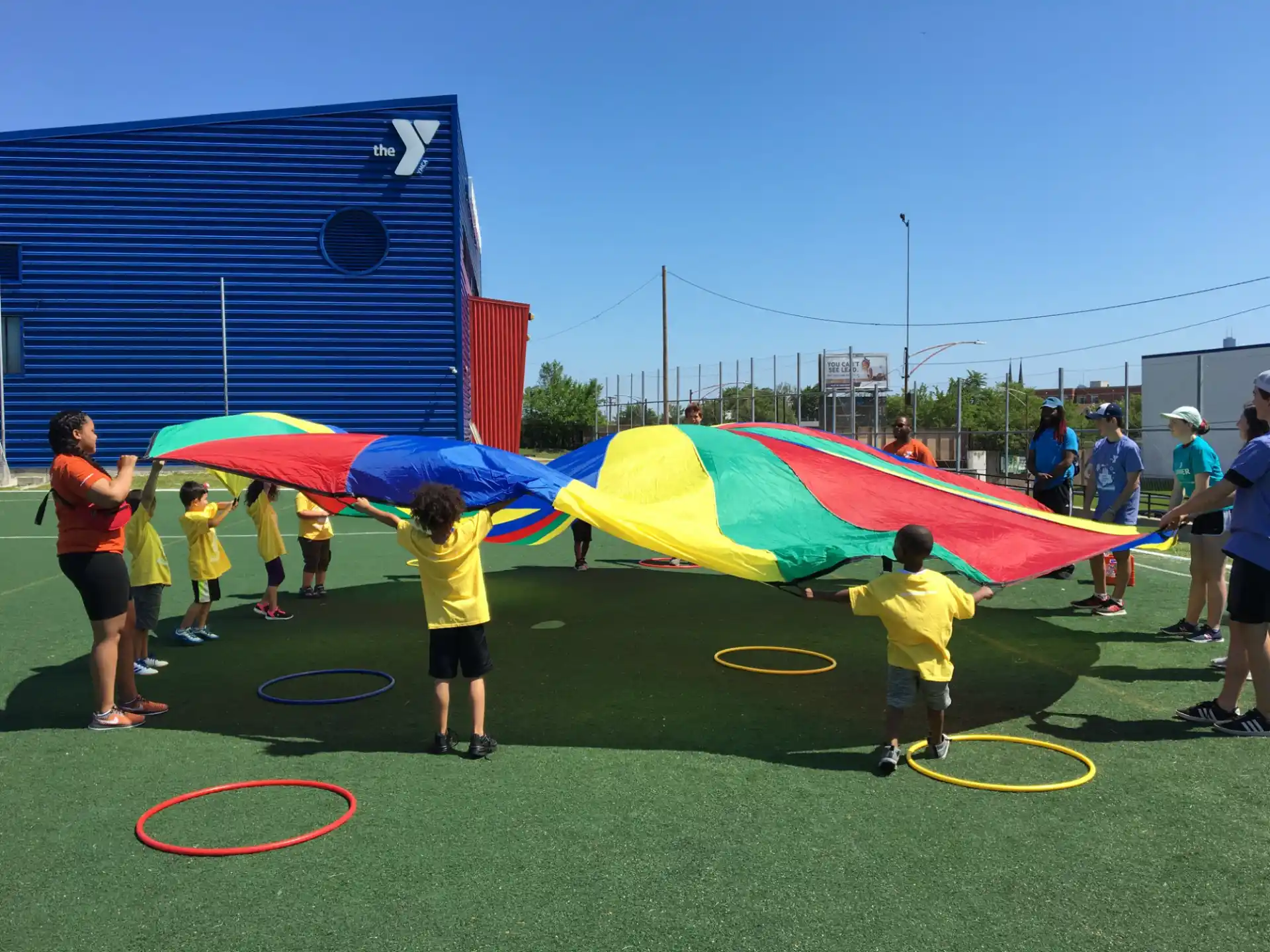 a group of people playing with a large colorful kite