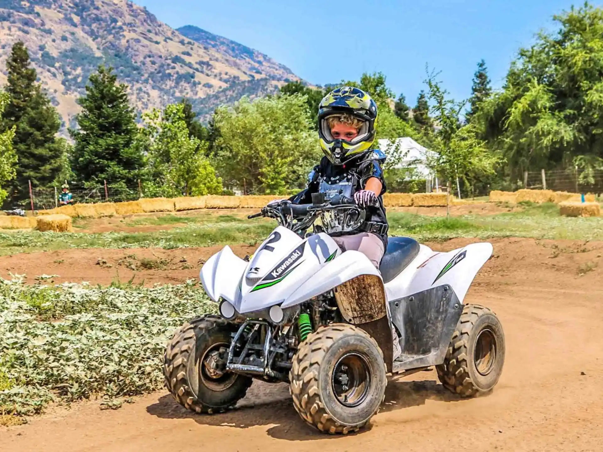 a person riding a vehicle on a dirt road with hills in the background