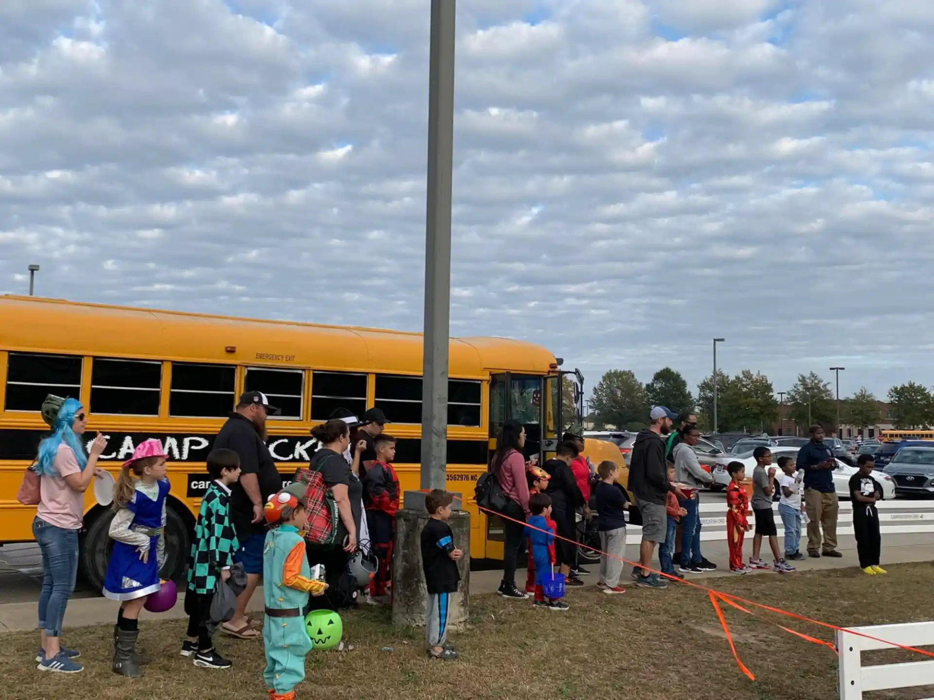 a group of people standing next to a yellow bus