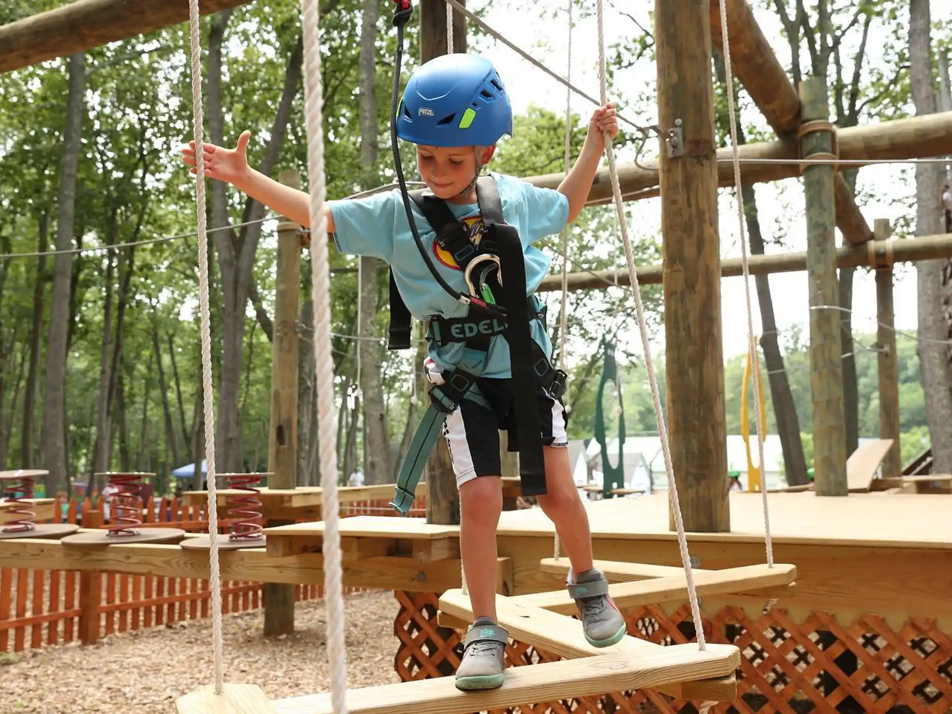 a boy wearing a helmet and climbing a wooden structure