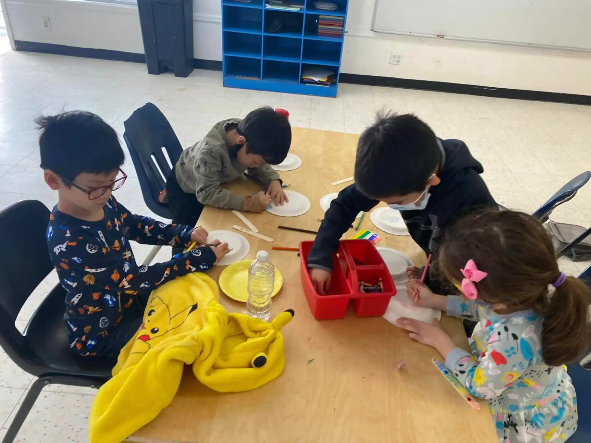 a group of children sitting at a table painting