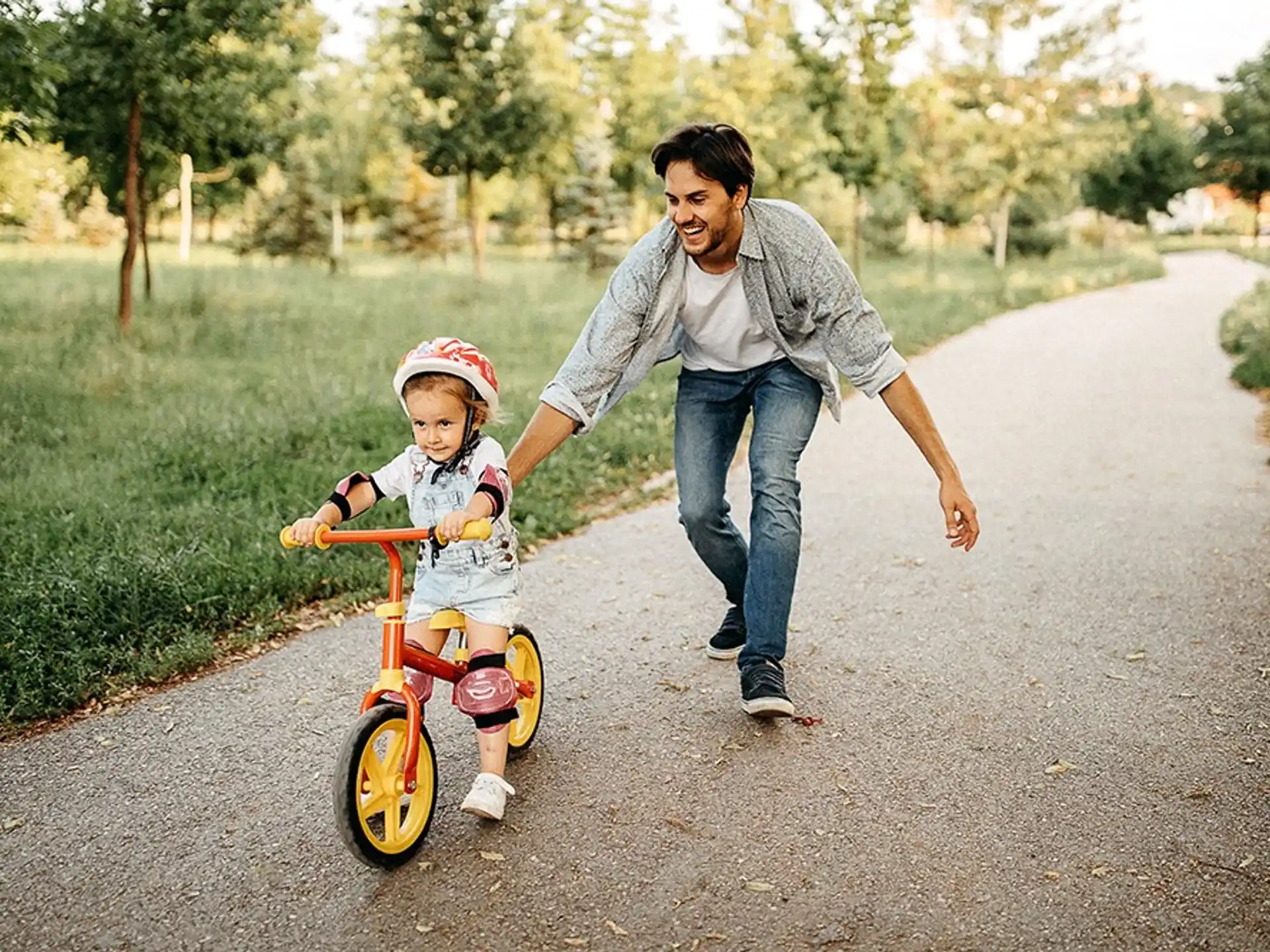 a man pushing a child on a tricycle