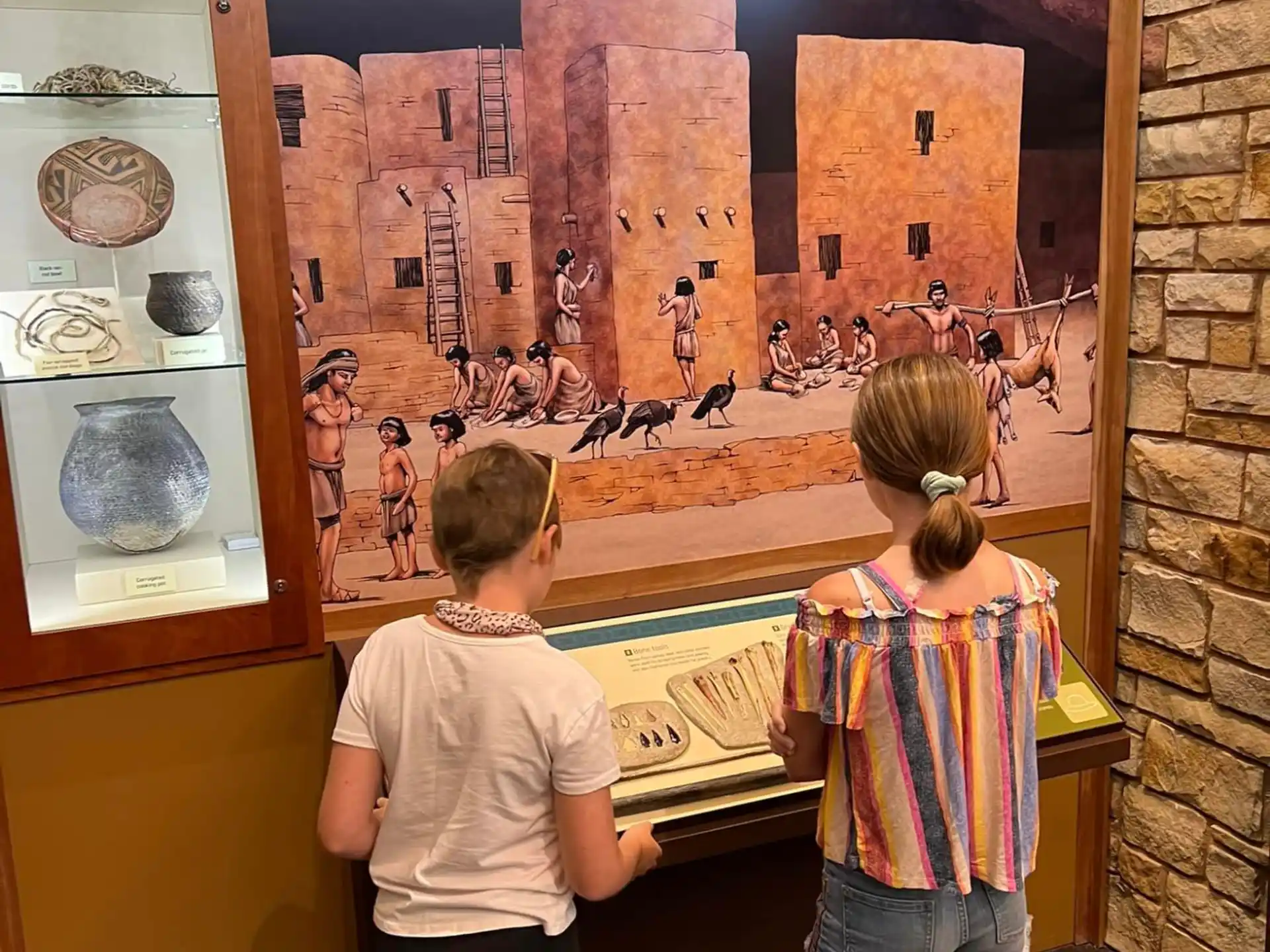 a couple of children looking at a painting on a wall
