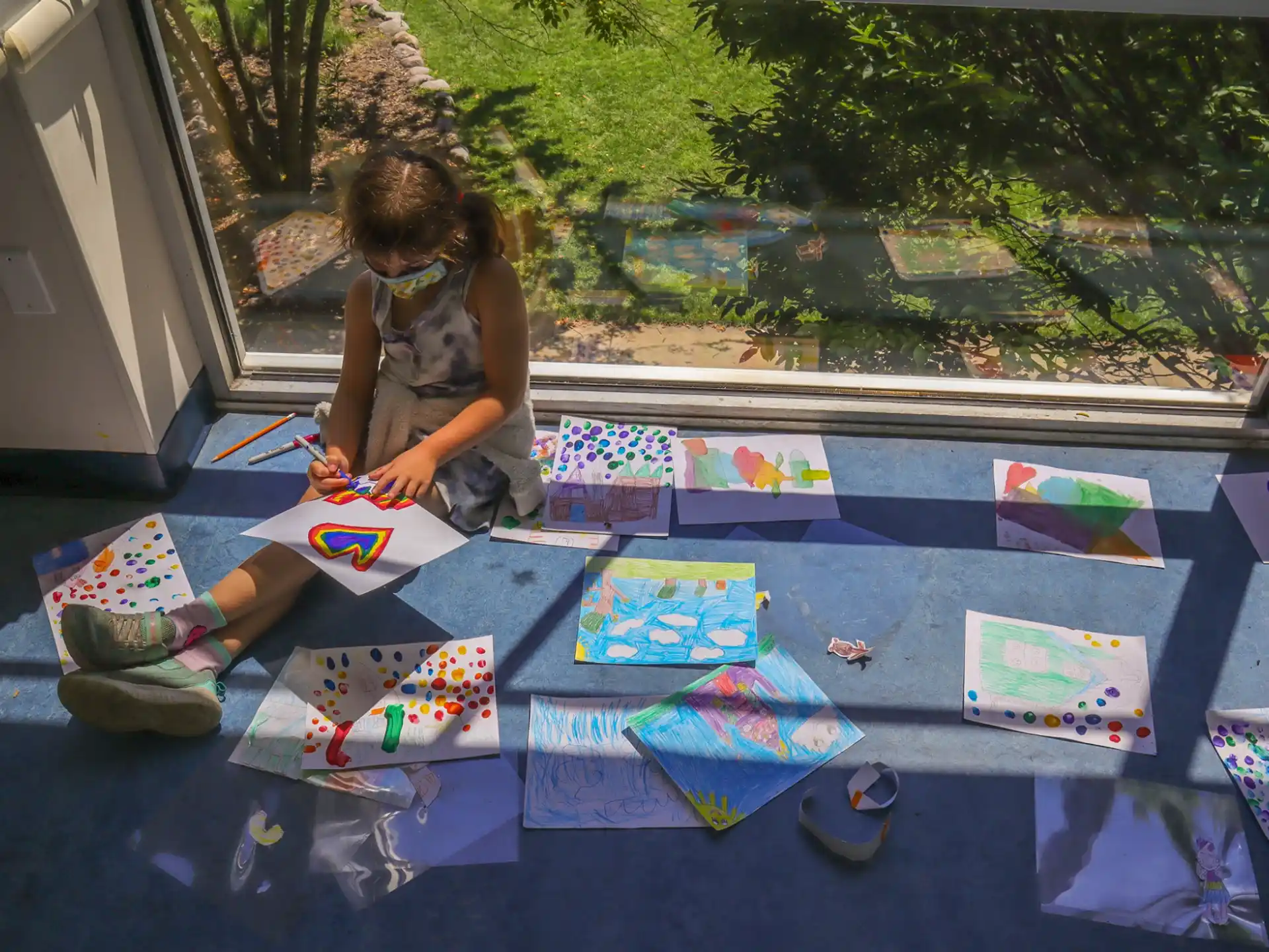 a child sitting on the ground with a group of colorful cards