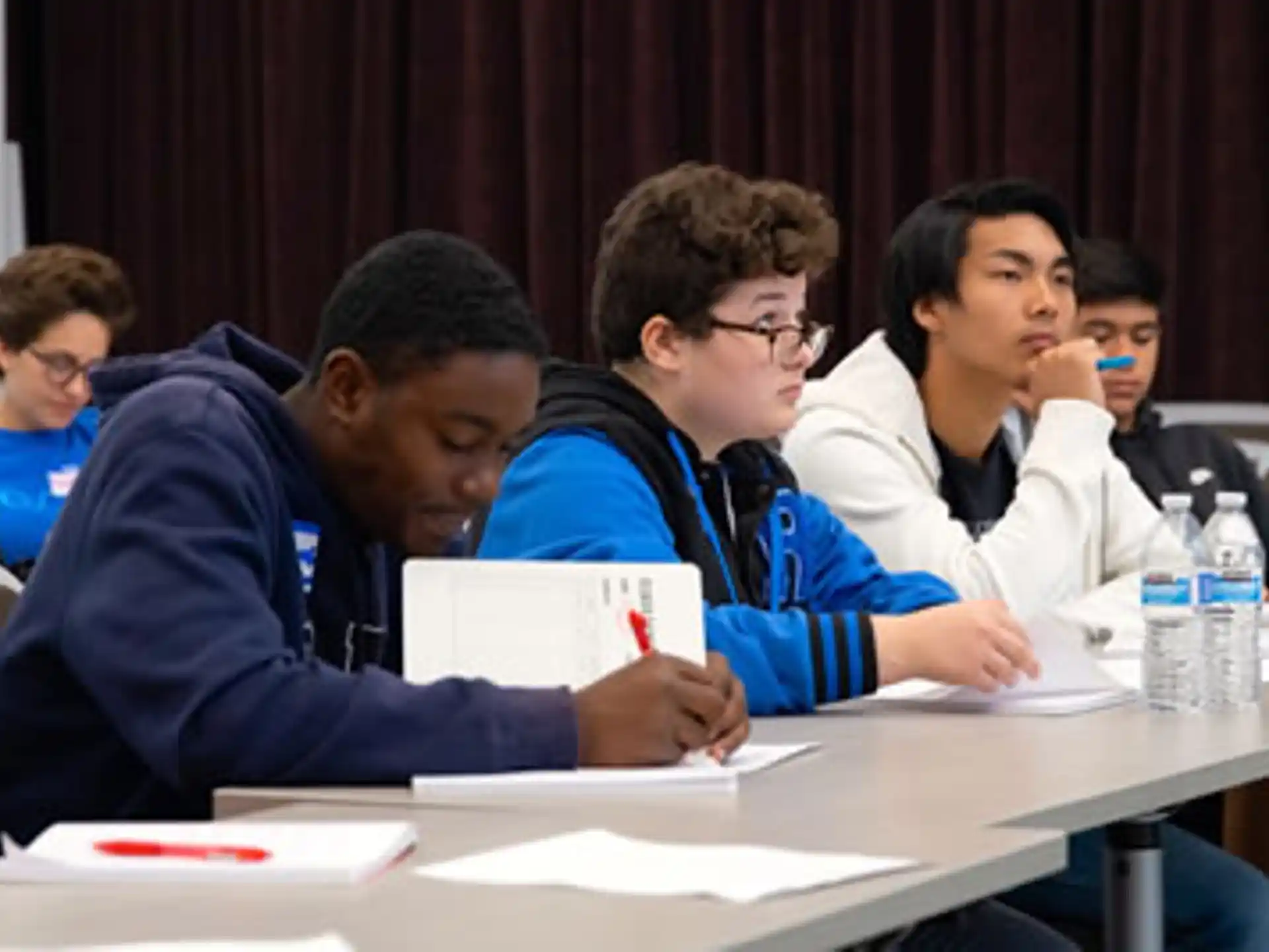 a group of people sitting at a table looking at papers
