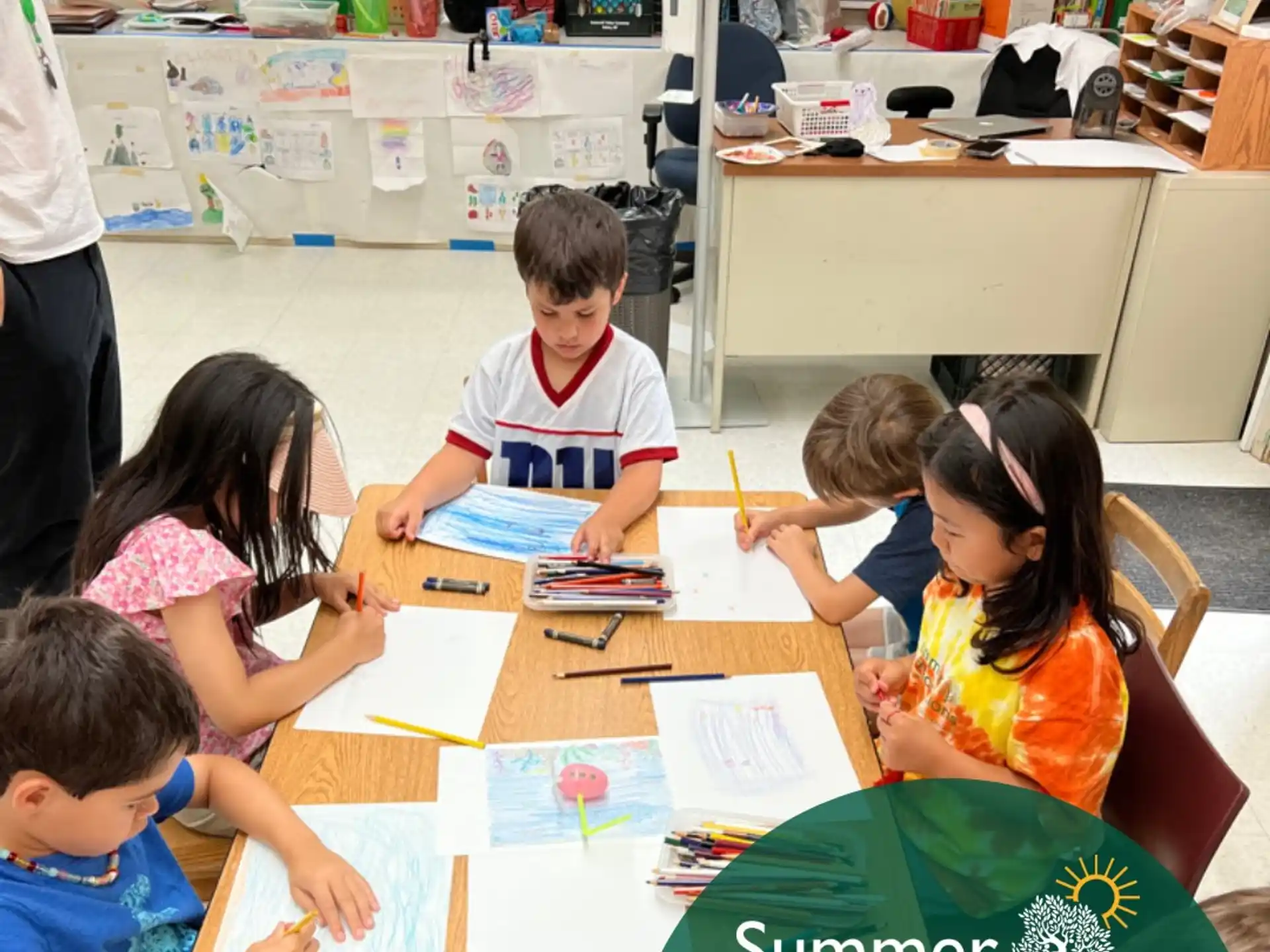 a group of children sitting at a table with a green sign