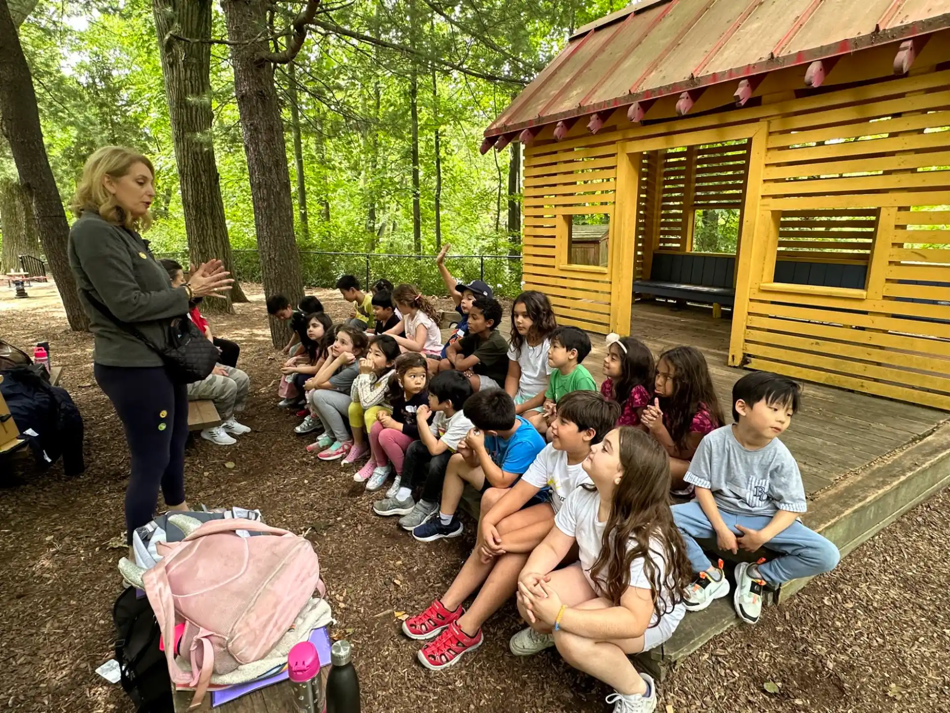 a person standing in front of a group of children sitting on the ground