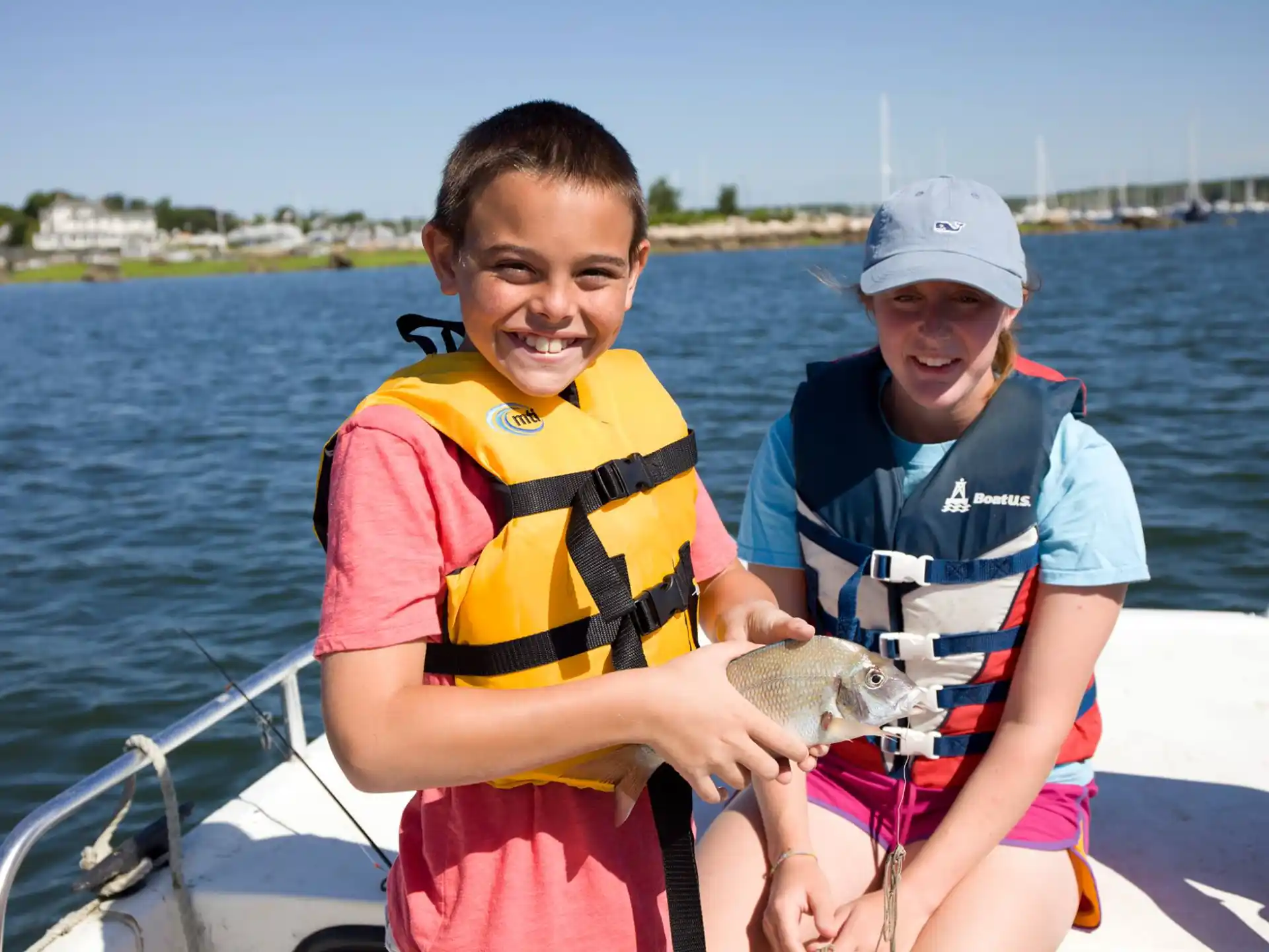 a couple of girls on a boat holding a fish