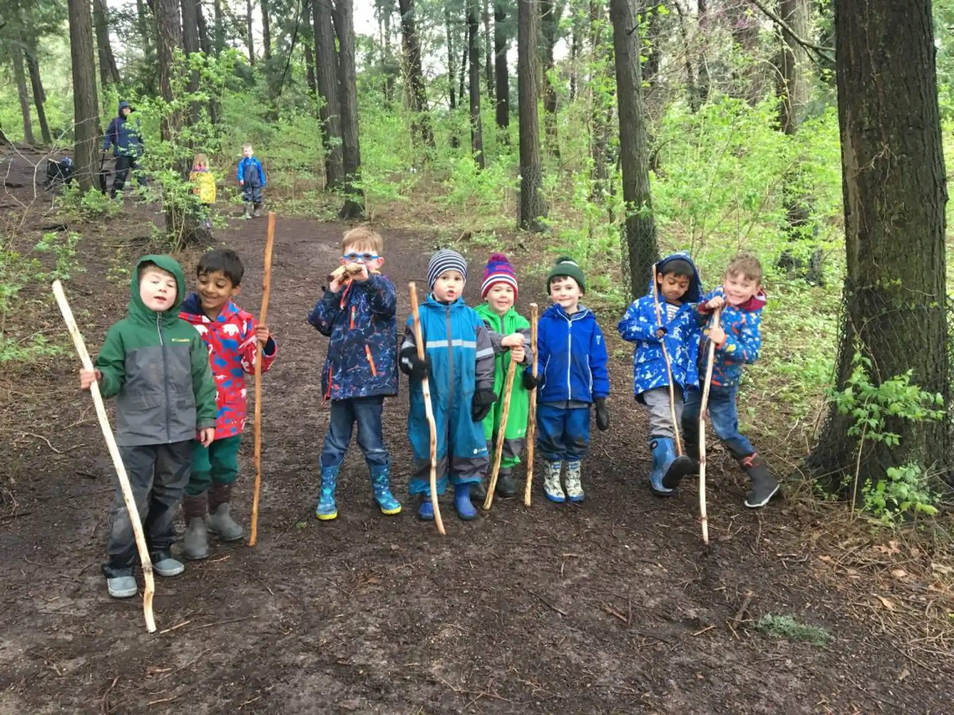 a group of children holding sticks in the woods