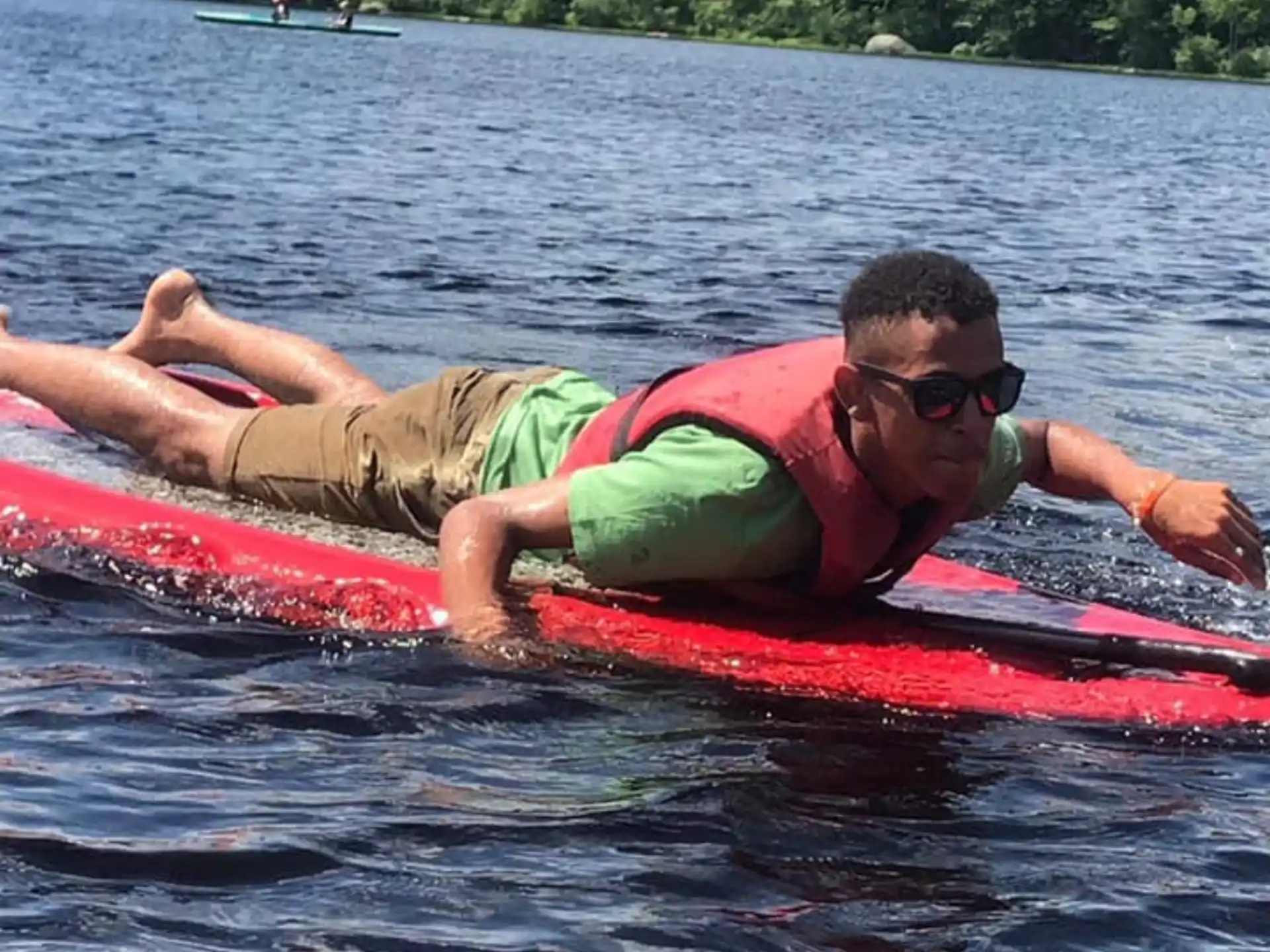 a person on a red inner tube in water with trees in the background